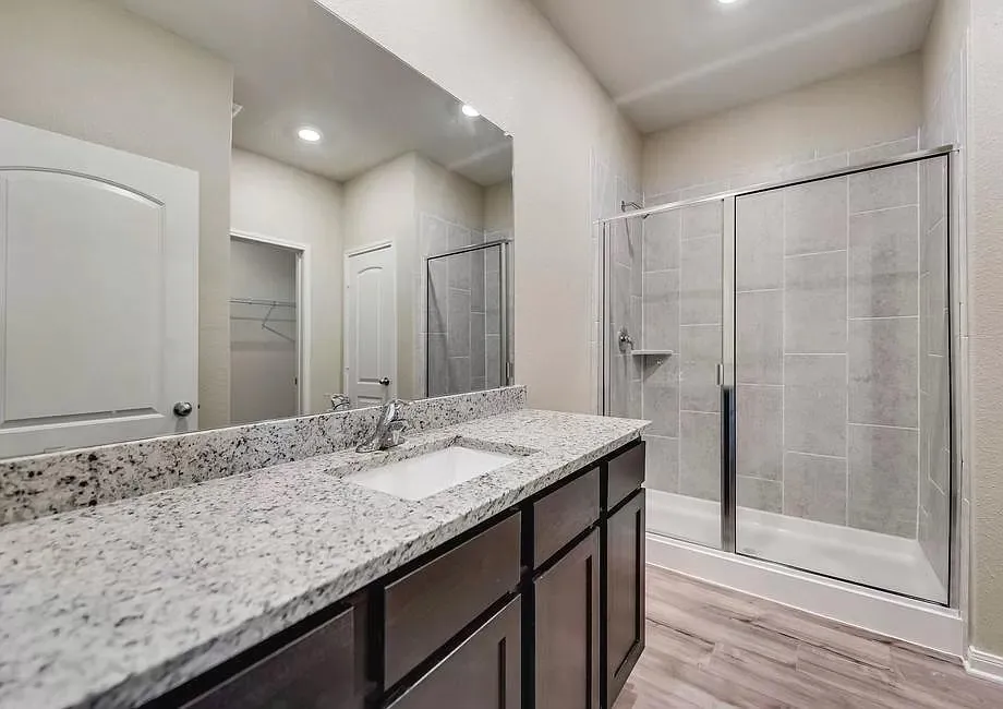 Spacious vanity with light-toned granite countertop, undermount sink, and dark wood-finish cabinetry