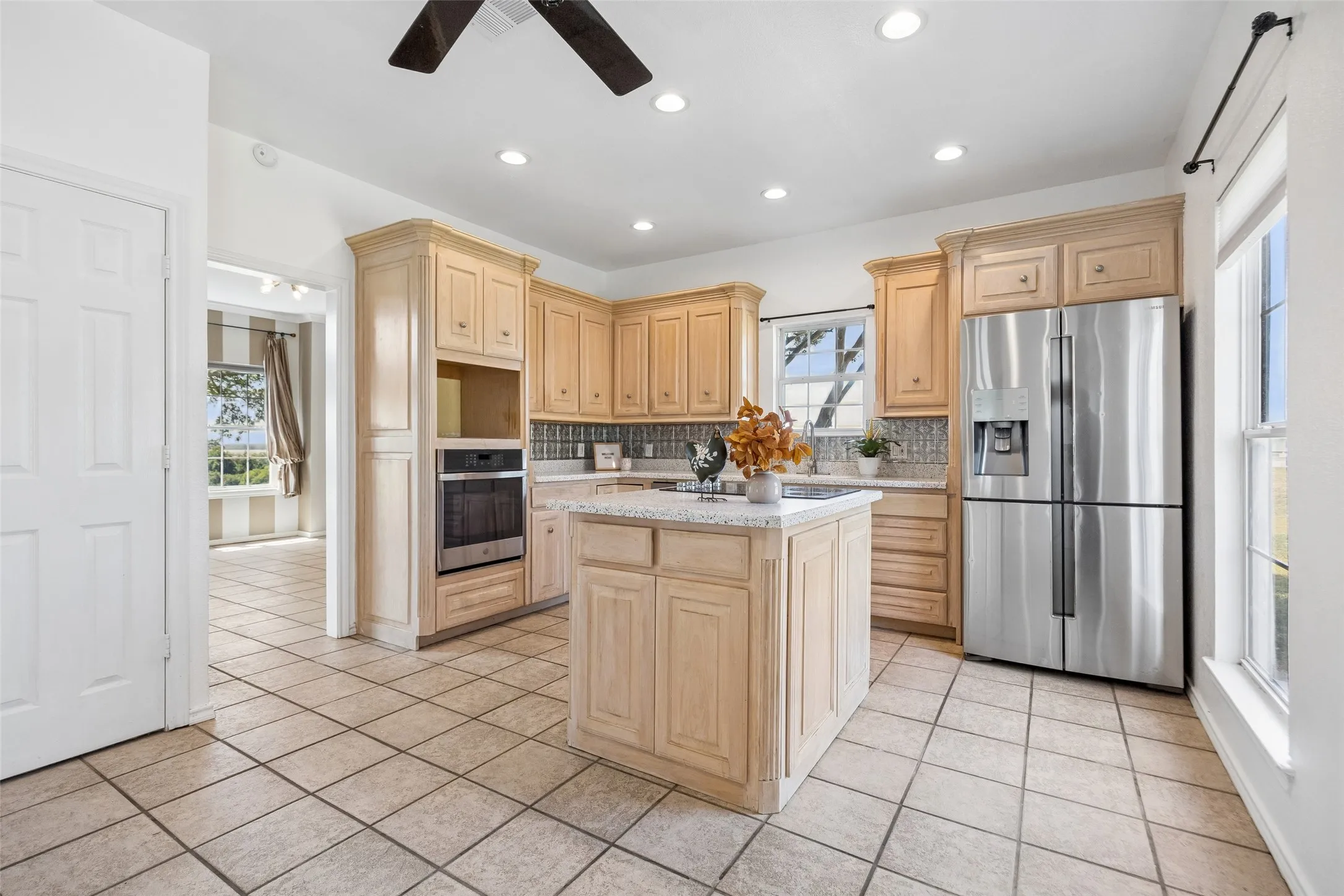 Kitchen featuring light wood cabinetry, a central island with a solid surface countertop, stainless steel appliances, and tile flooring