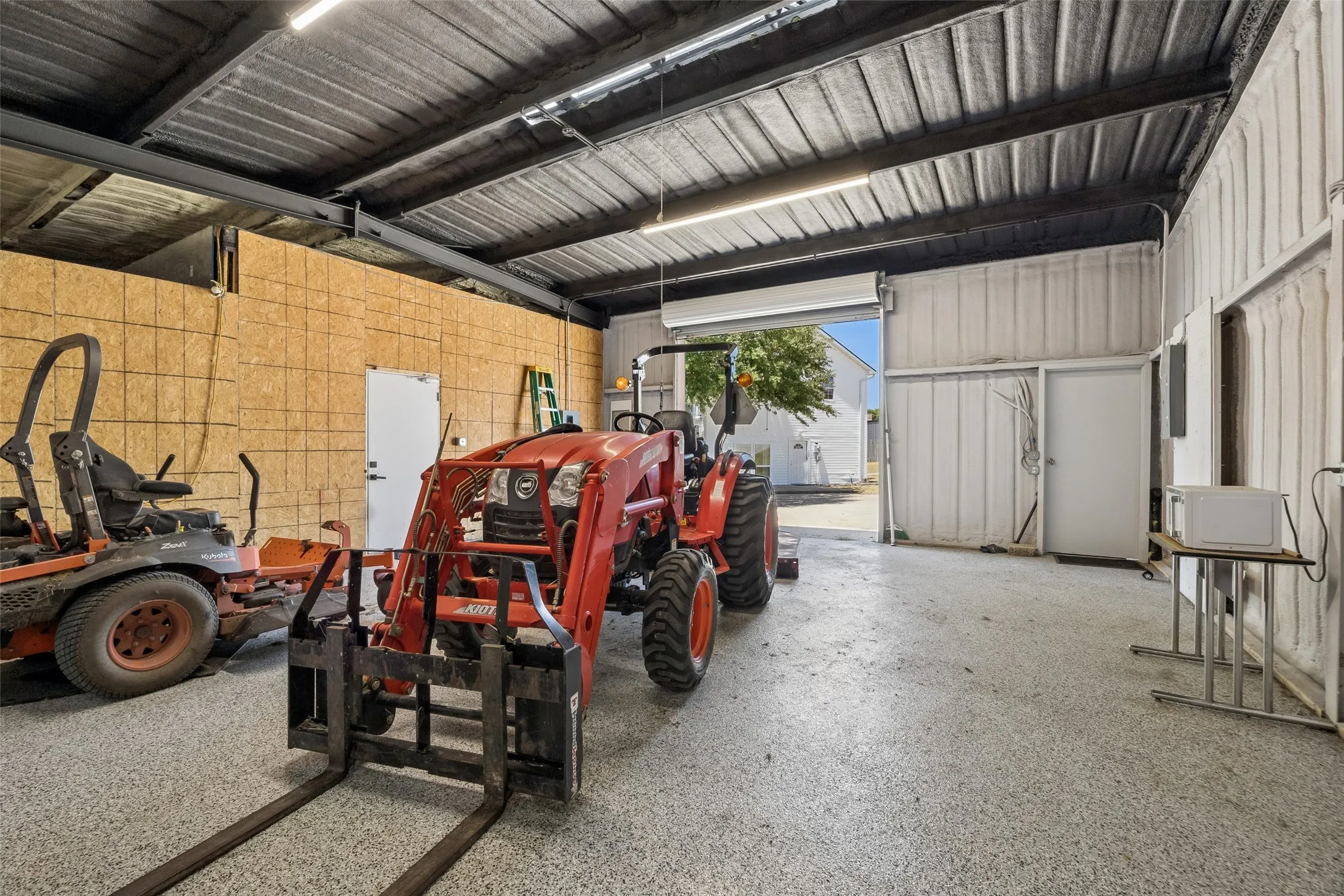 Spacious garage with an overhead door, smooth concrete flooring, and ample overhead lighting