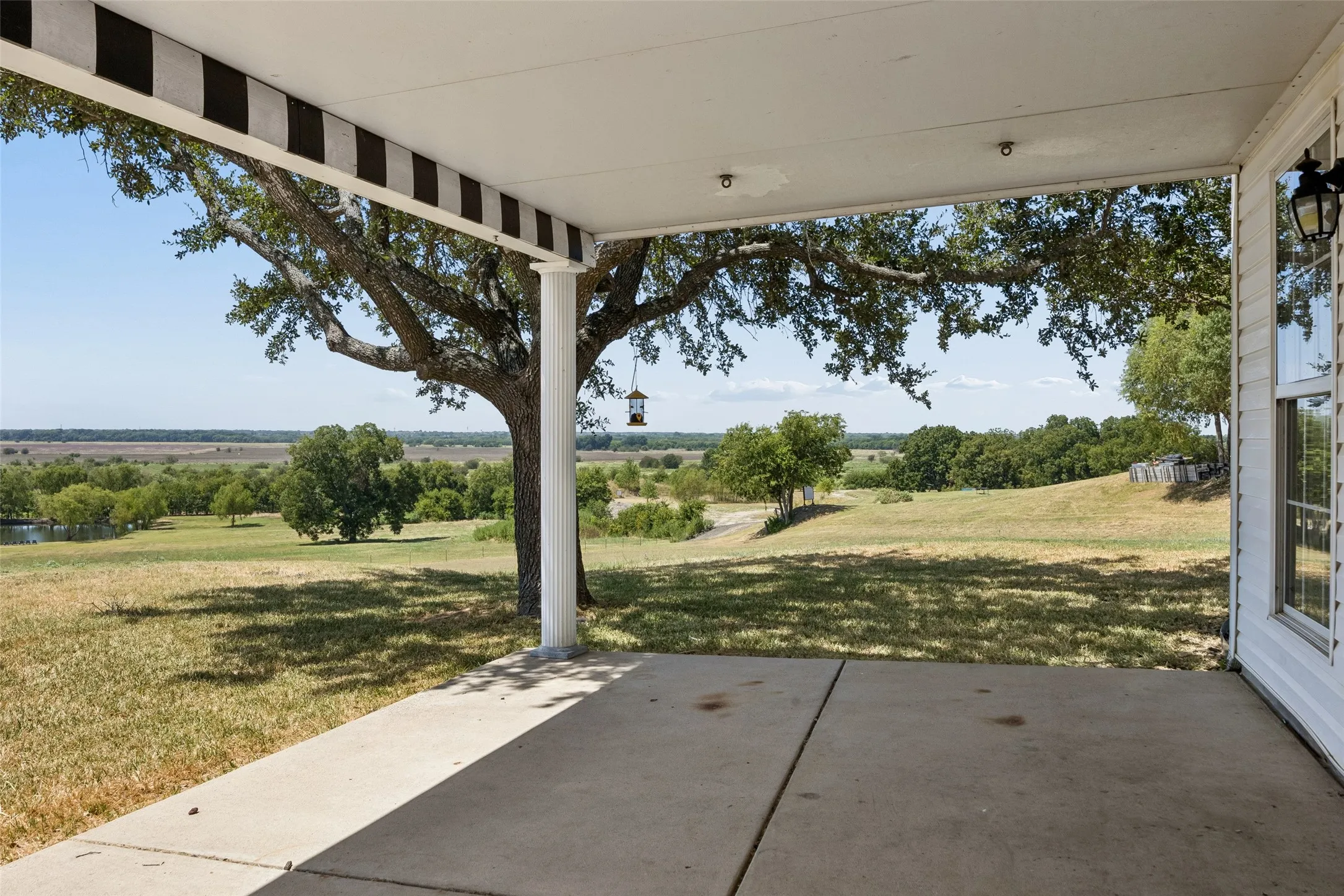 Covered concrete patio with a column support and white exterior siding