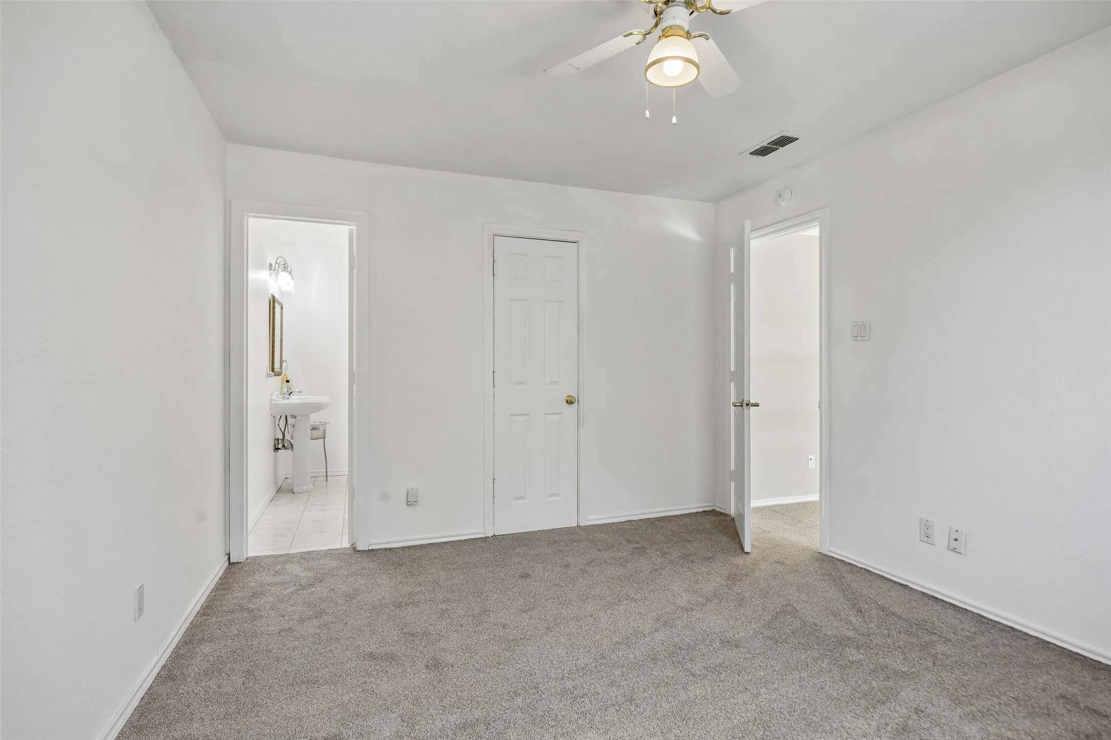 Secondary bedroom 1 with Carpeted flooring, white walls, ceiling fan, white paneled doors, and a pedestal sink with a framed mirror