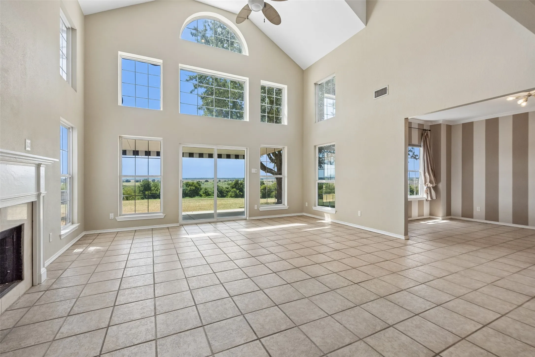 Grand vaulted ceilings with all of windows, a fireplace with a mantel, and tiled flooring
