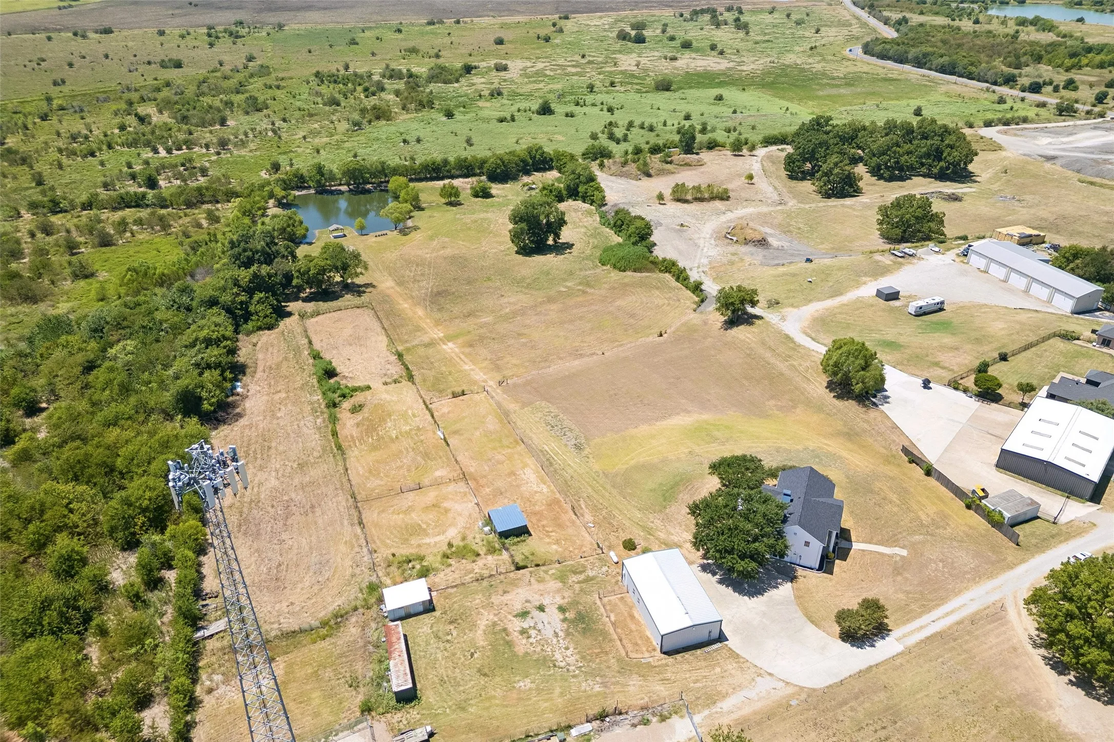 Expansive acreage with a pond, diverse vegetation, and multiple outbuildings
