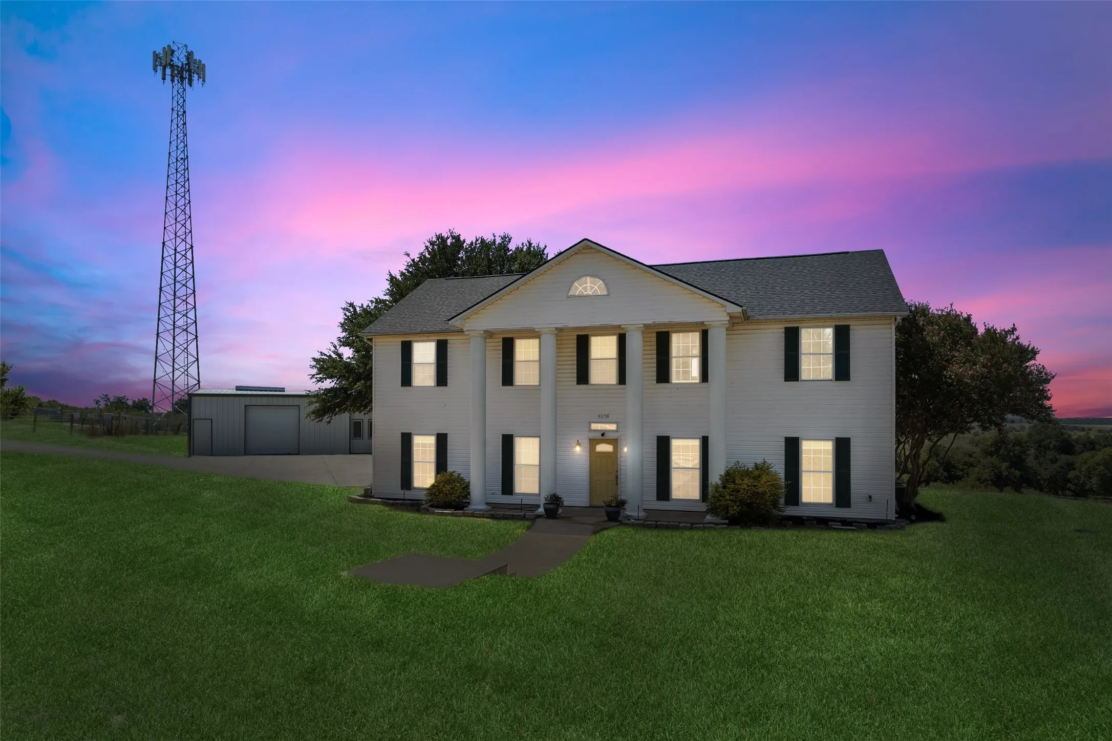 Colonial-style facade featuring prominent white columns, dark shutters, and a central entry