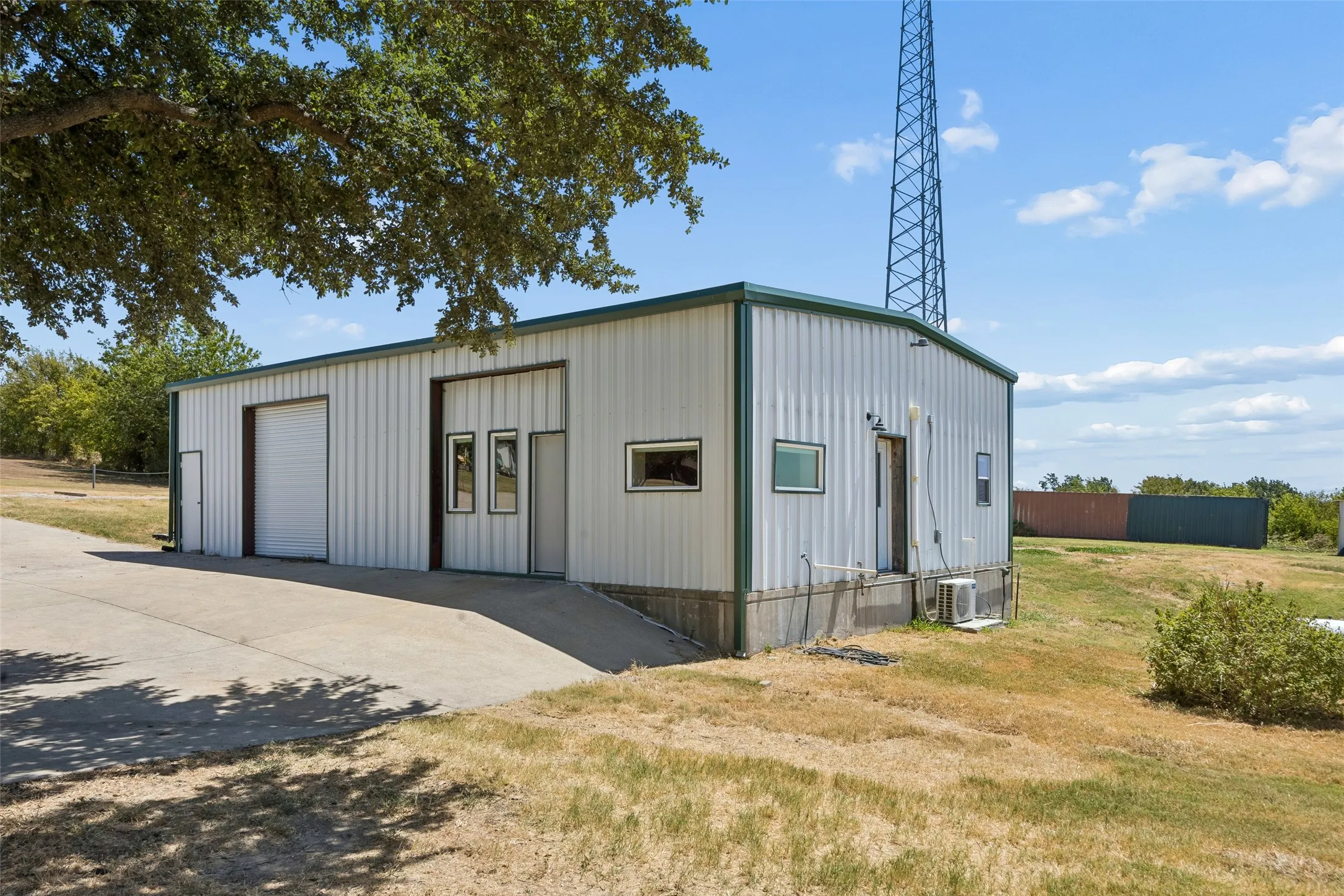 Metal-sided structure featuring multiple roll-up doors, various window configurations, and a private entry door