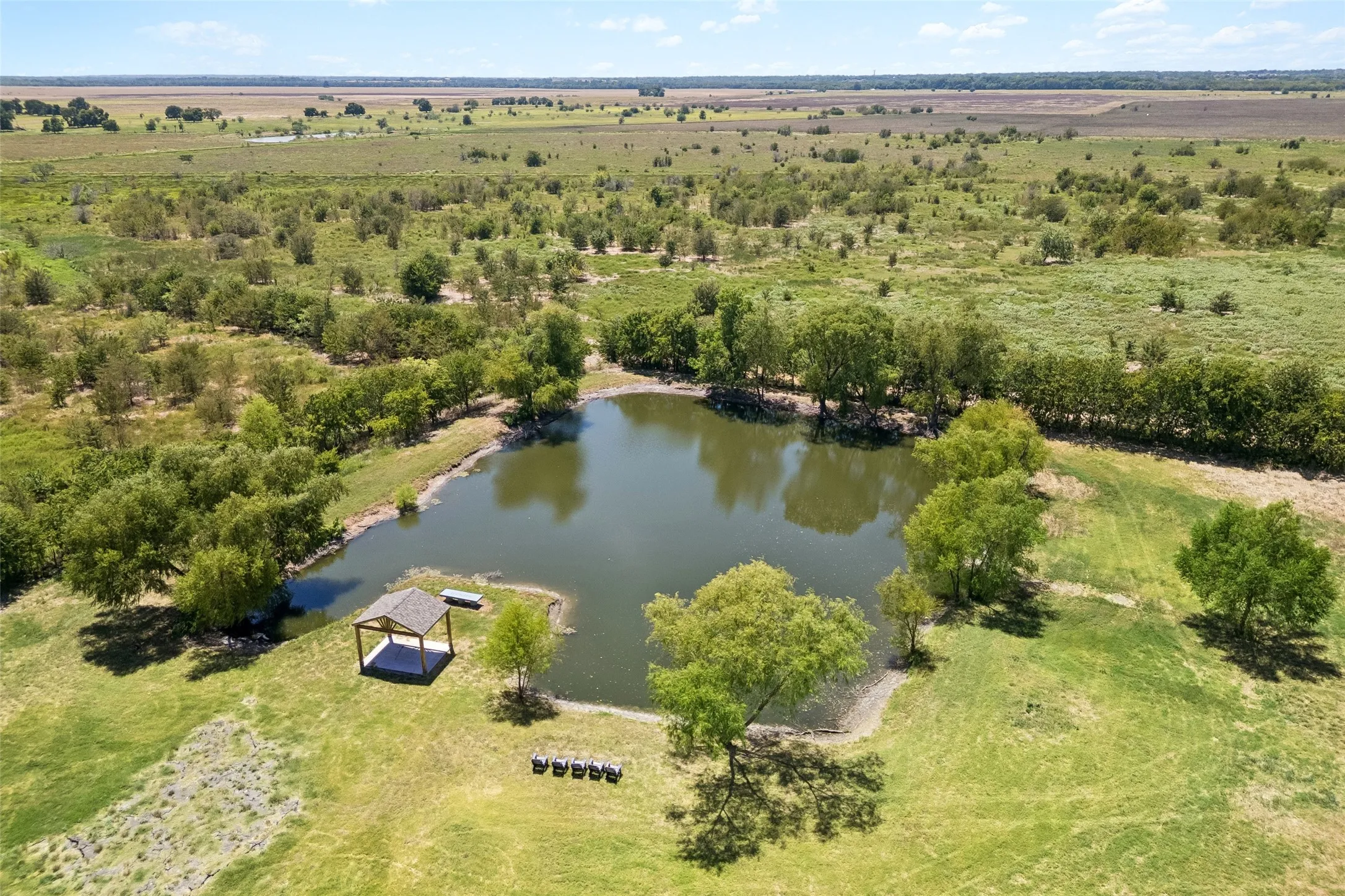 Expansive natural pond & landscape featuring a prominent pond with a shaded gazebo structure