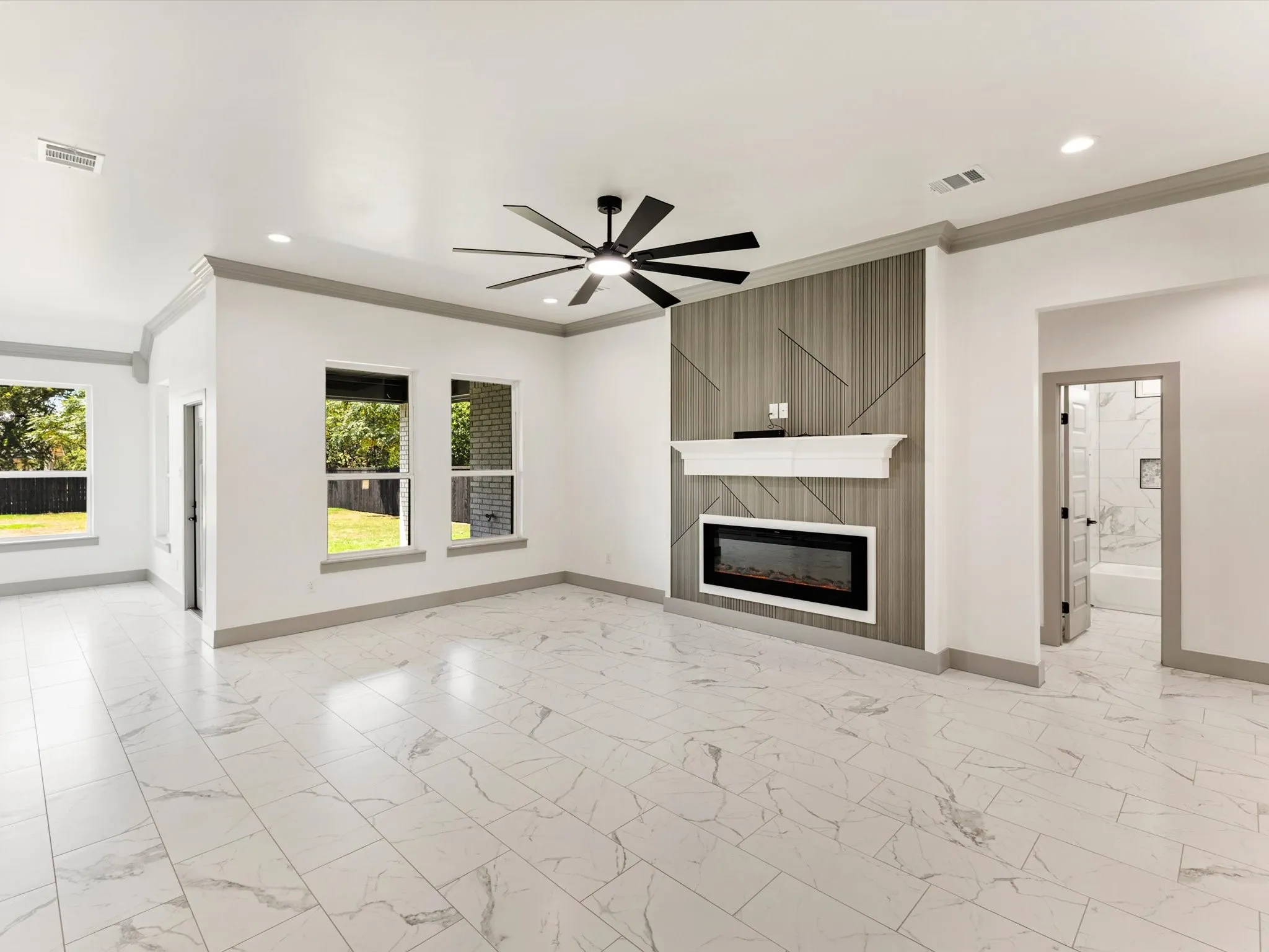 Rectangular tile flooring, decorative fireplace with mantel, ceiling fan with integrated lighting, recessed lighting, and multiple windows
