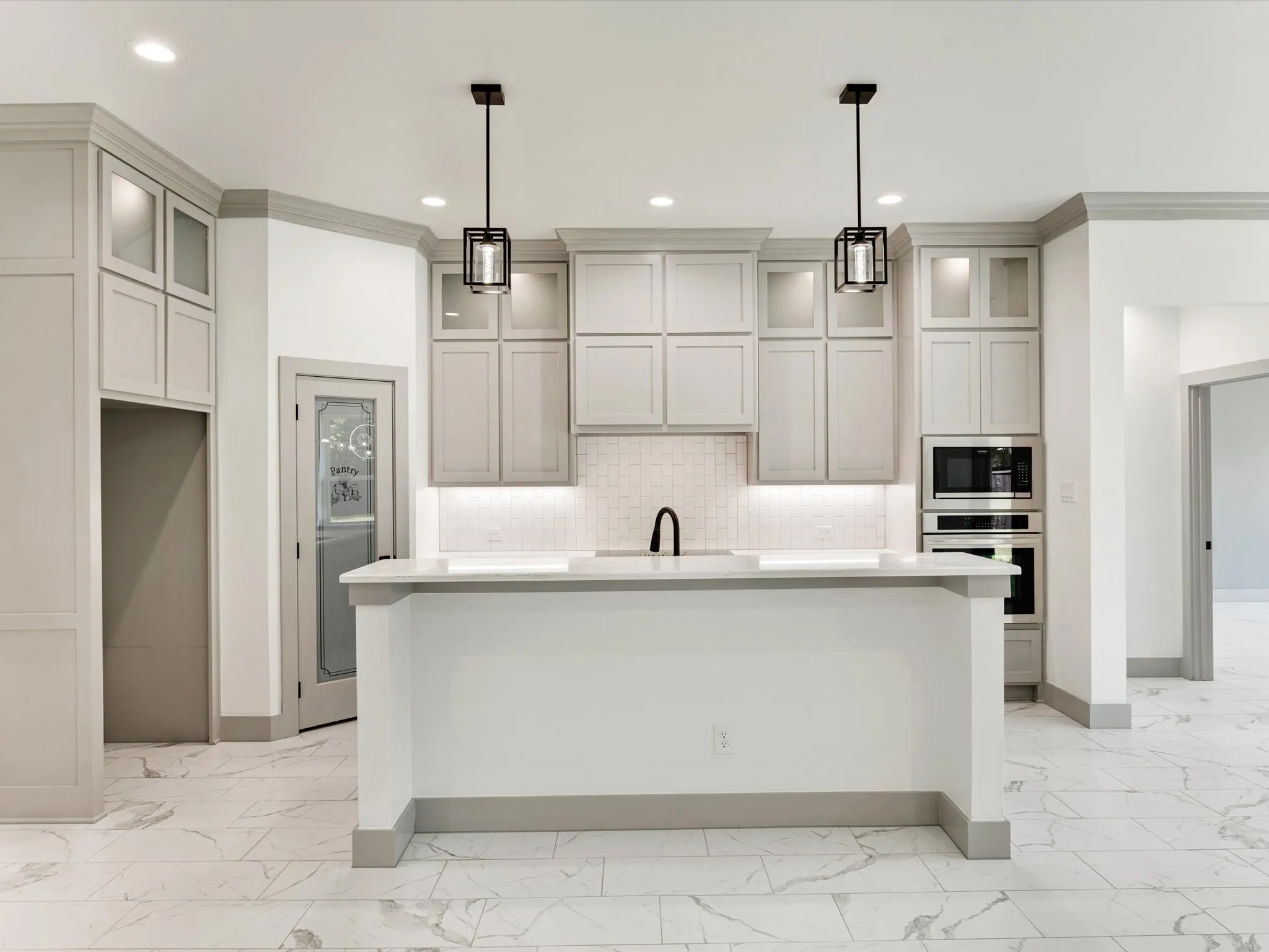 Kitchen featuring light-toned cabinetry, a central island, integrated wall oven and microwave, recessed lighting, and pendant fixtures