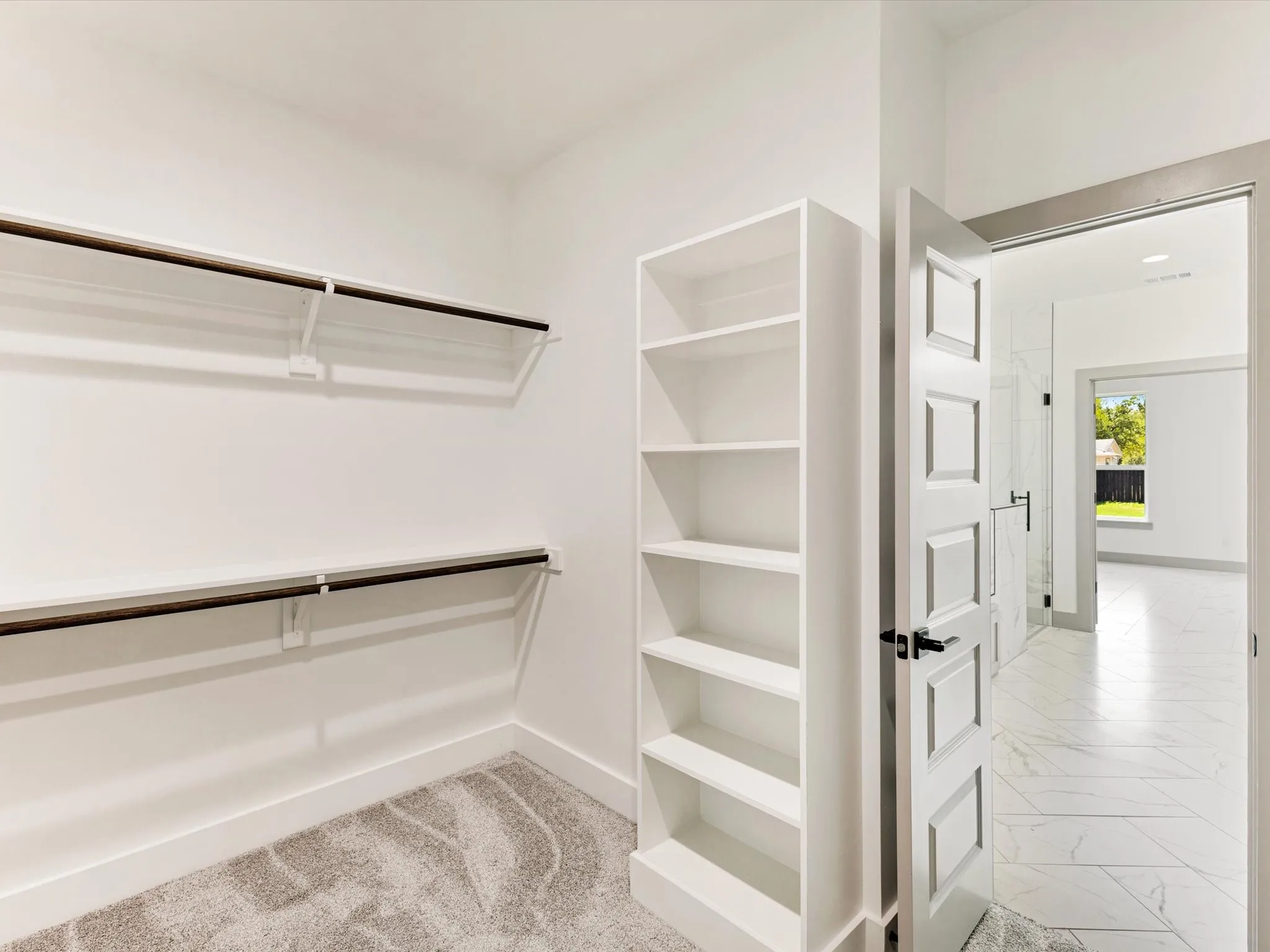 Built-in shelving, hanging rods, patterned carpet, paneled interior door, and tiled flooring