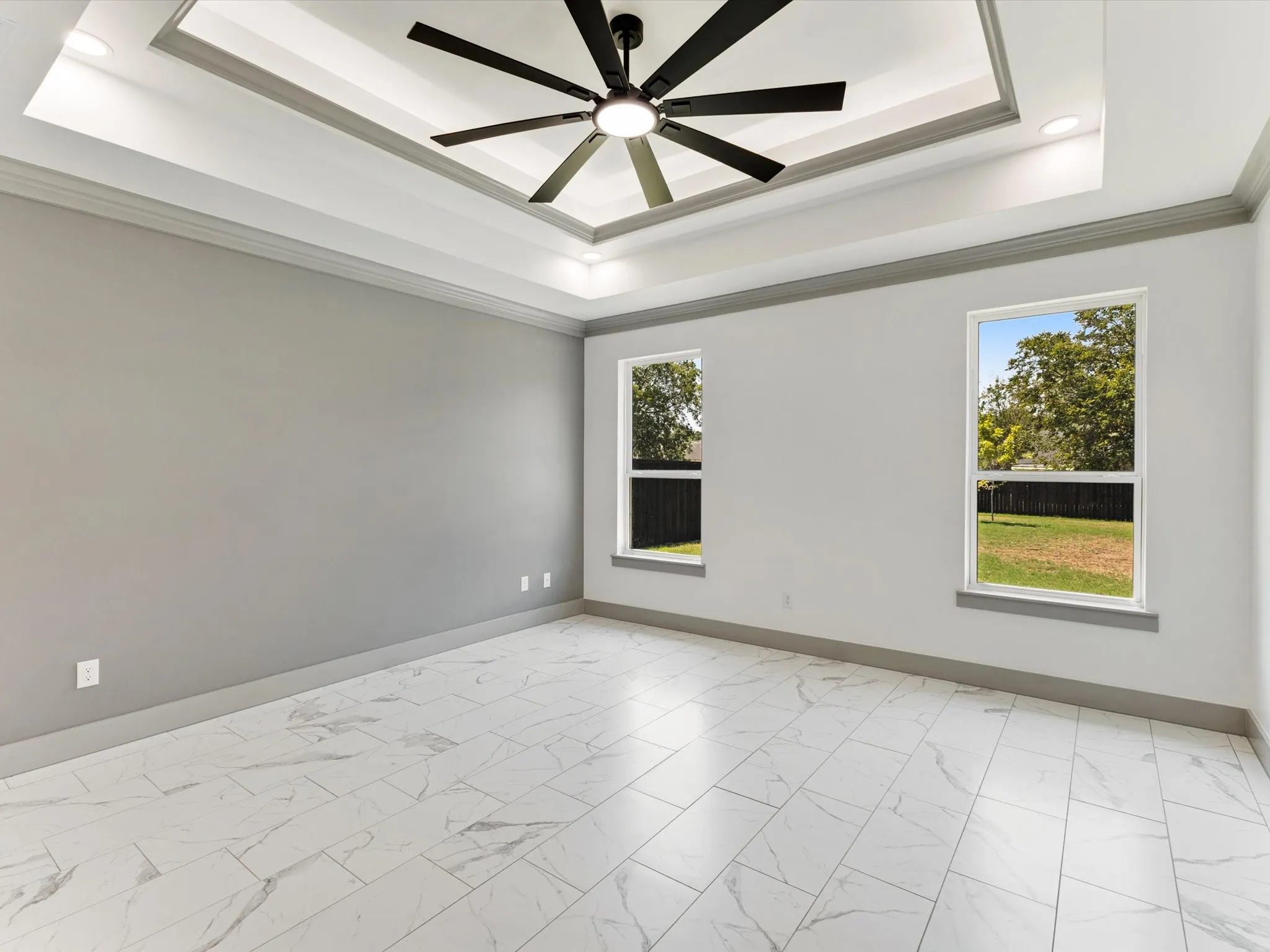 Tray ceiling with recessed lighting and a ceiling fan, bright interior with two windows, and patterned tile flooring