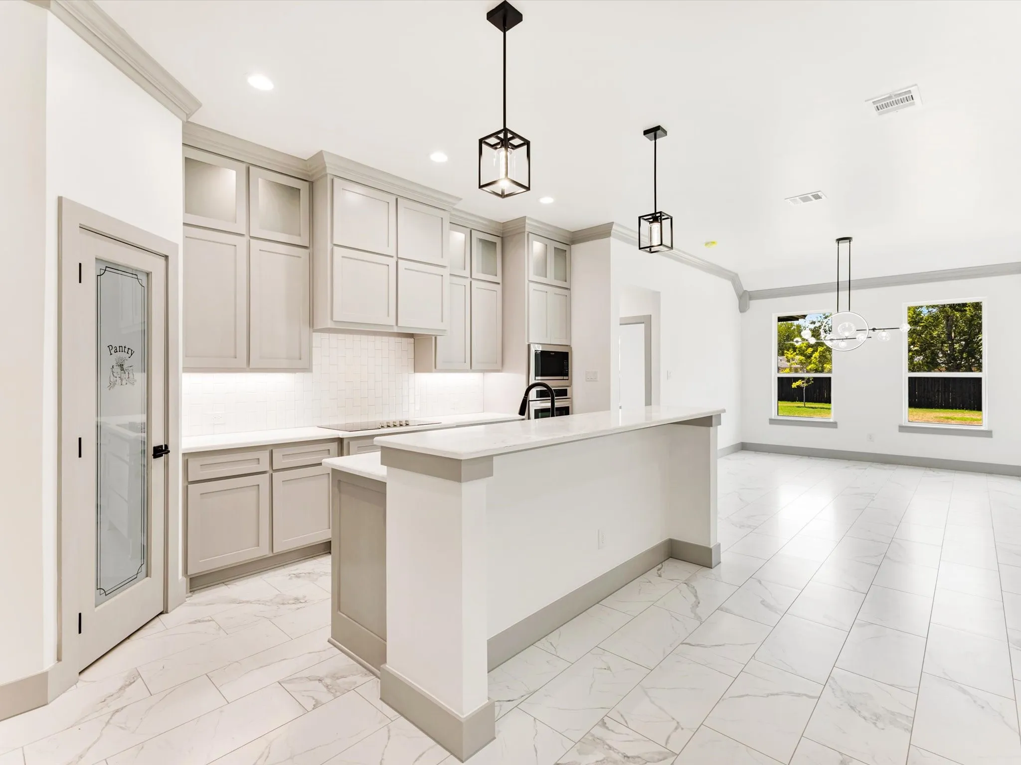 Modern kitchen featuring light cabinetry, a peninsula island with seating, pendant lighting, and tile flooring
