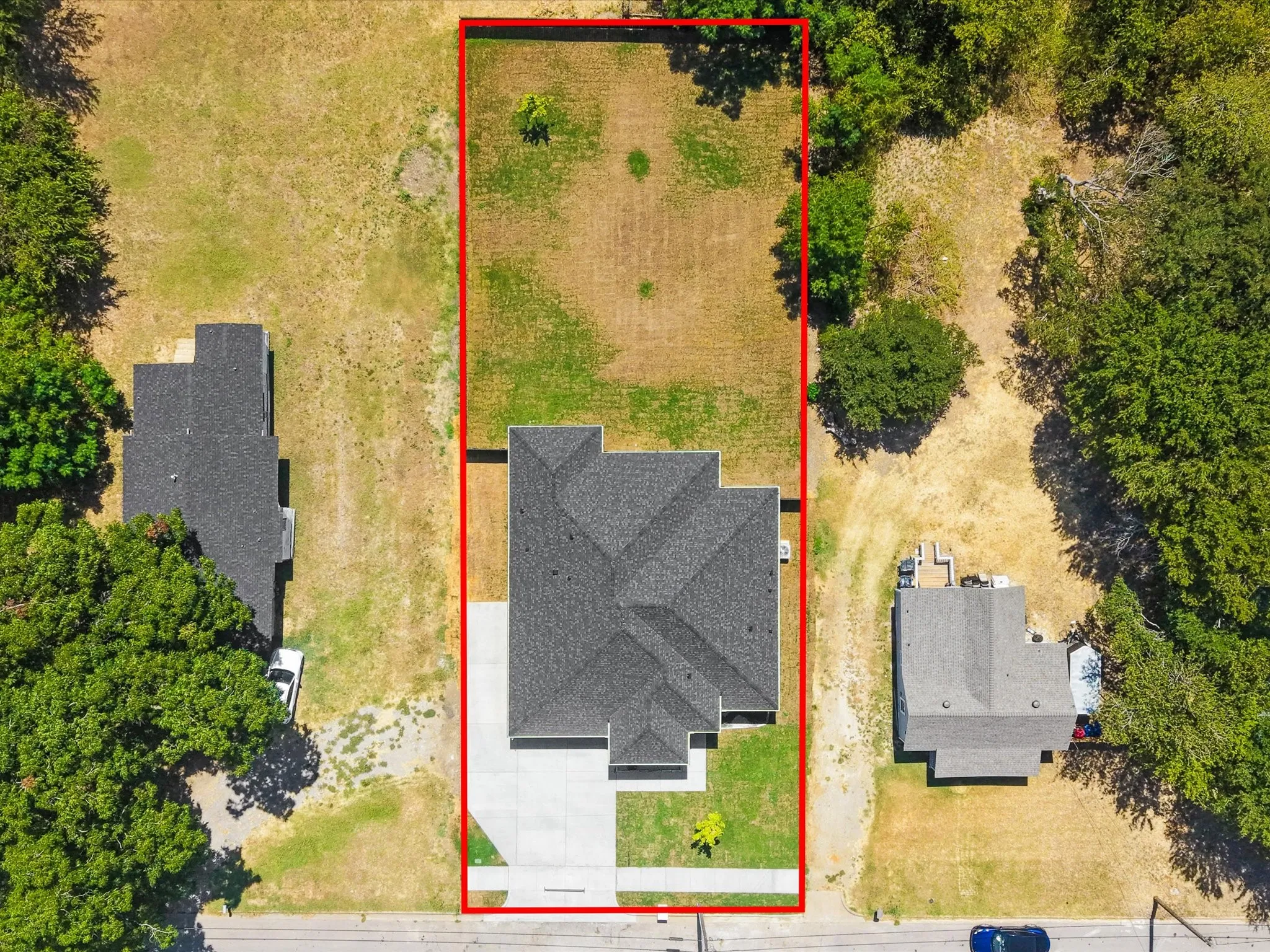Aerial view showcasing a spacious lot with mature landscaping and tree-lined perimeter