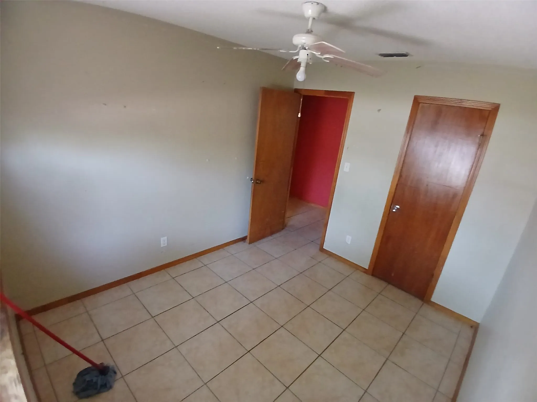 Light-colored tile flooring, overhead ceiling fan with light fixture, wood-finish interior doors