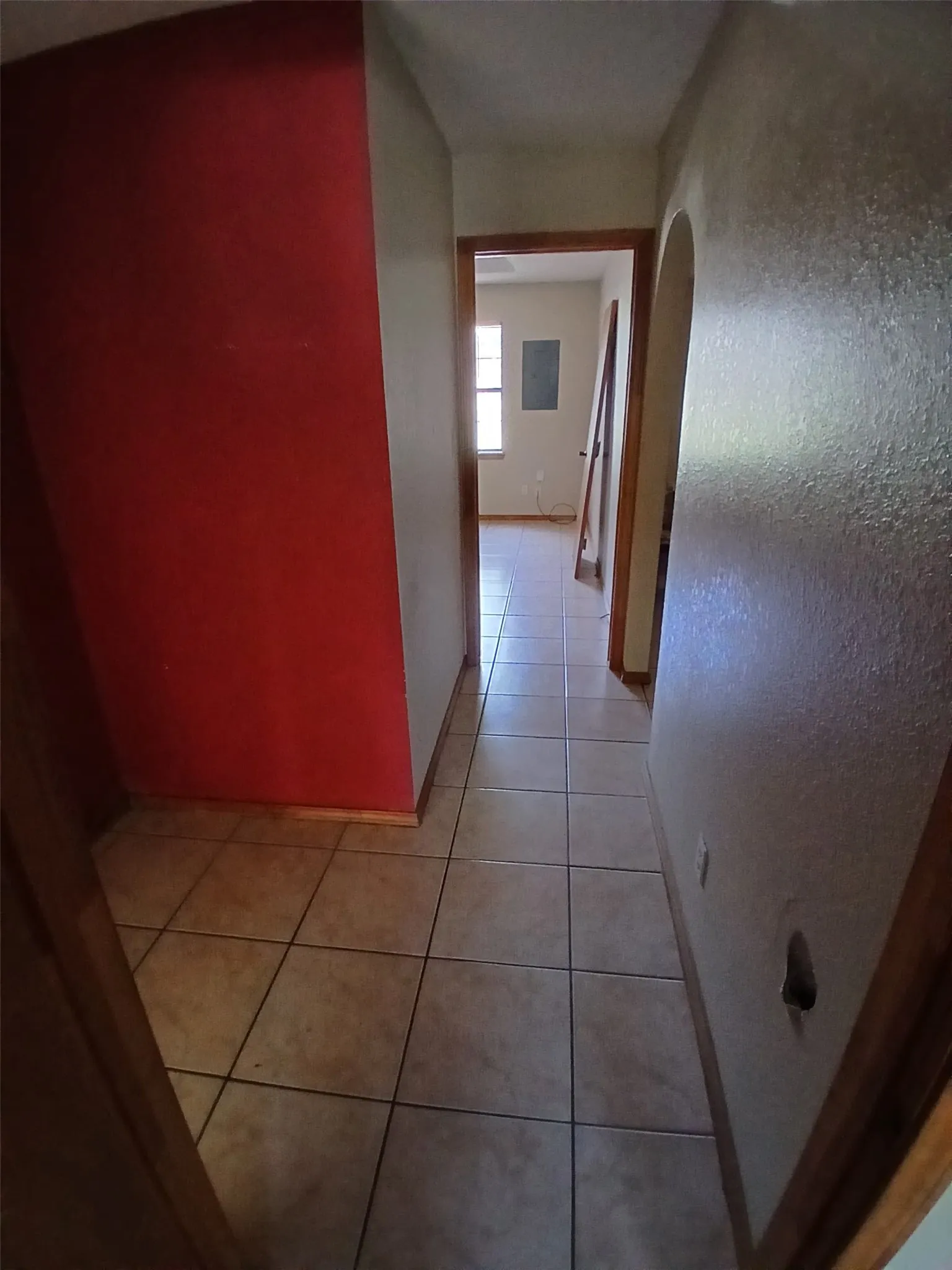 Tiled flooring extends through the hallway with wood-trim door frames and an arched entryway