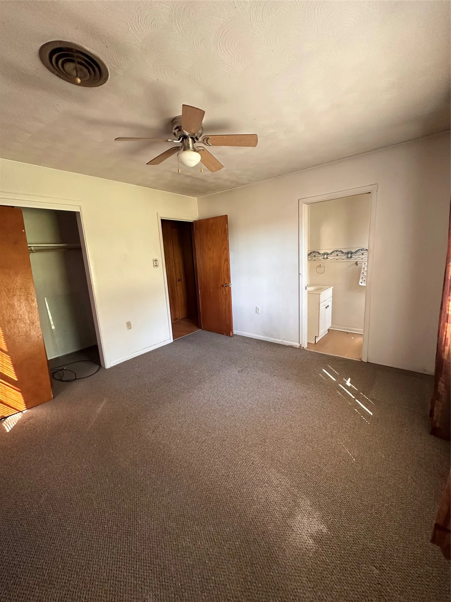 Carpeted room with a ceiling fan, a built-in closet, and an attached washroom featuring a vanity sink