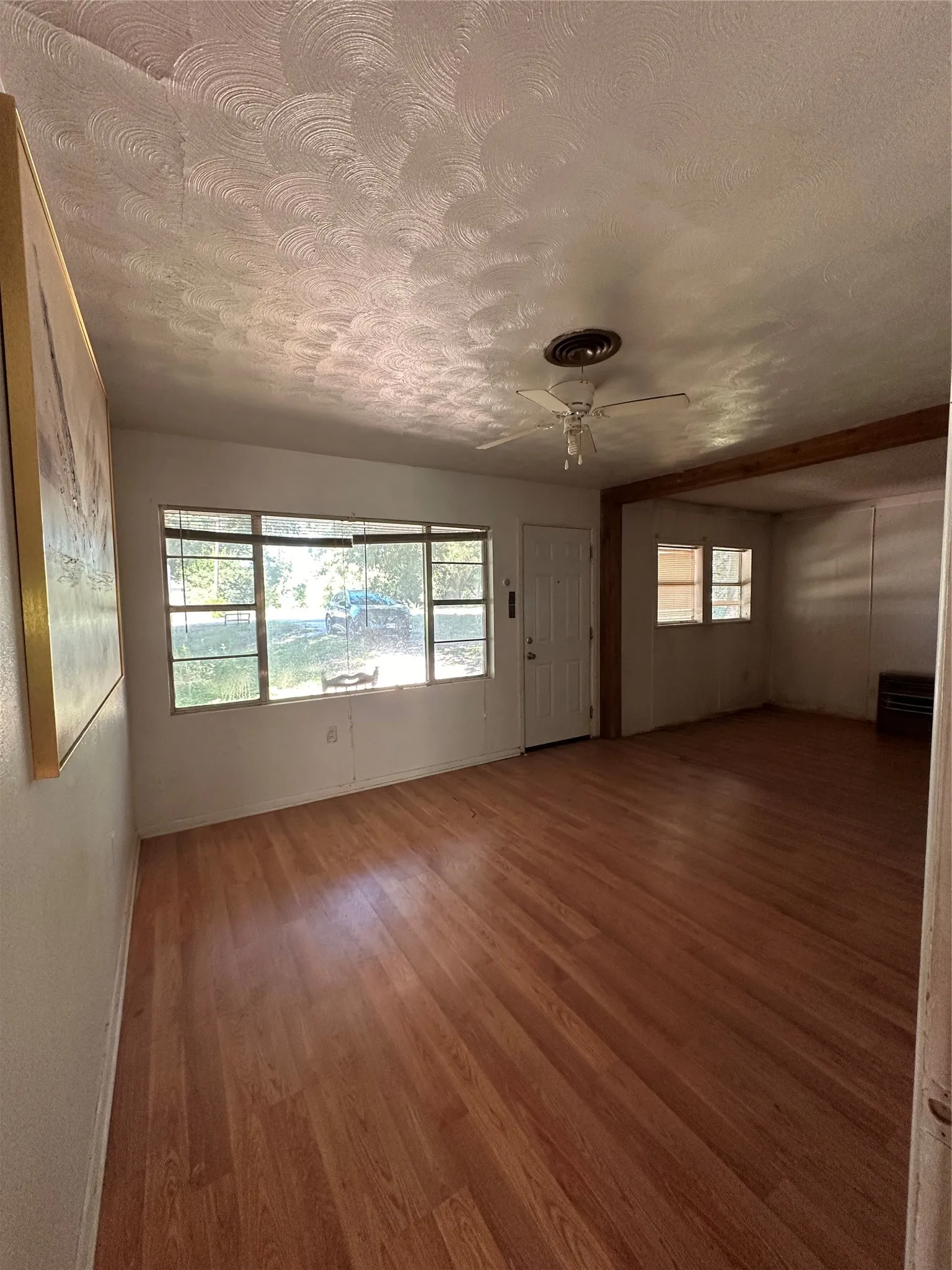 Spacious interior with wood-finish flooring, large windows, and a ceiling fan