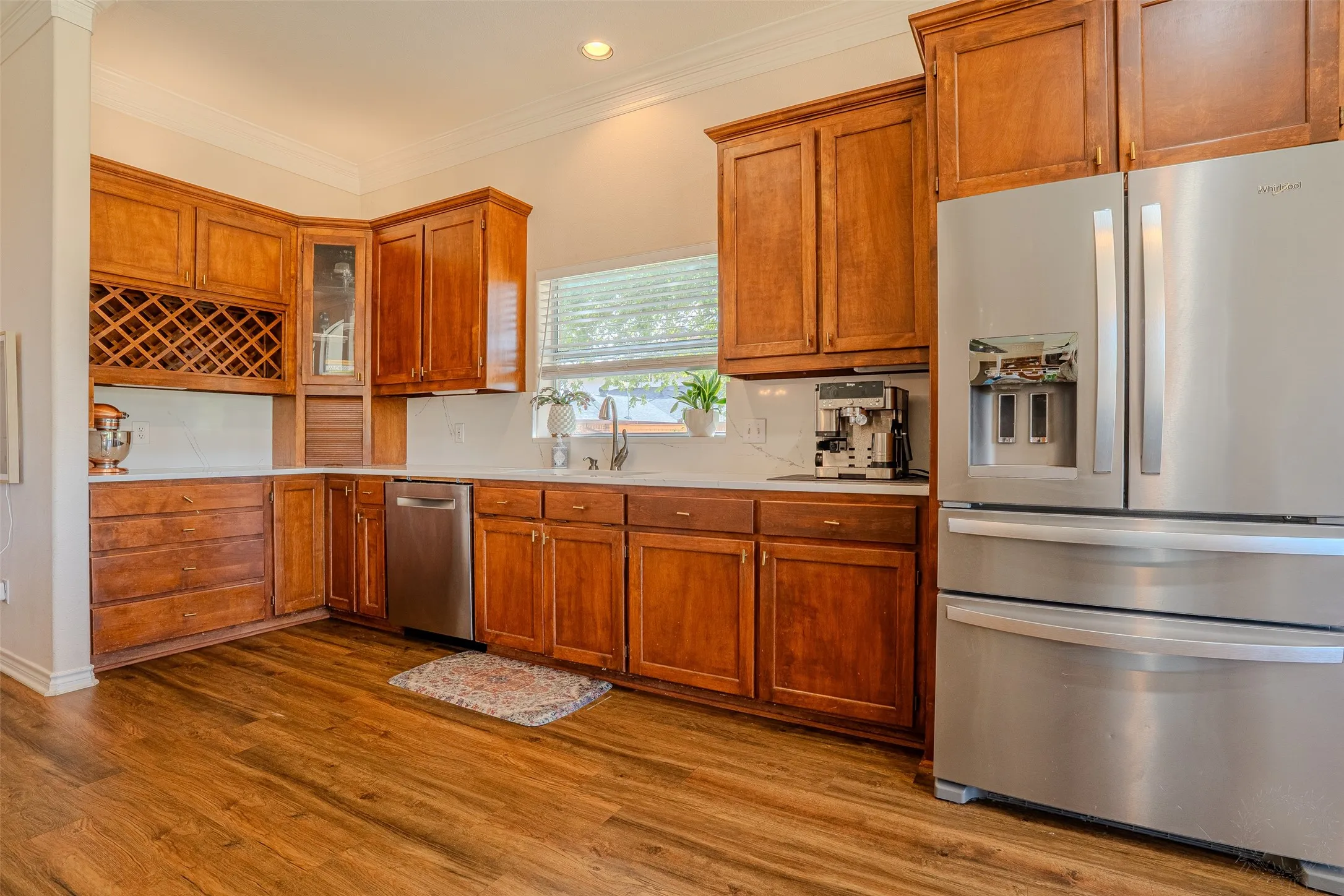 Well-appointed kitchen featuring wood-finish flooring, ample wood cabinetry, white countertops, and stainless steel appliances