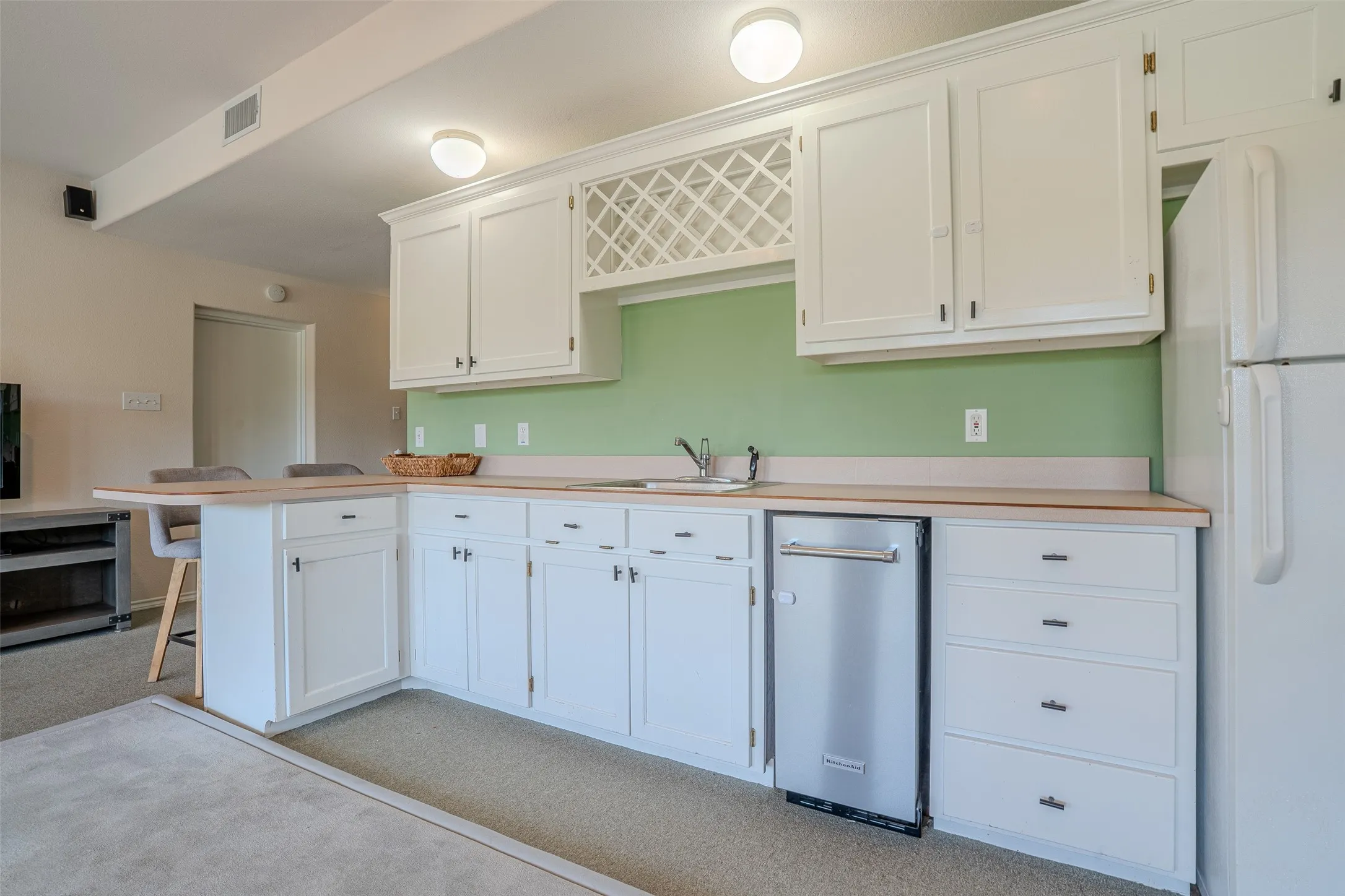 White cabinetry with a built-in wine rack and stainless steel dishwasher