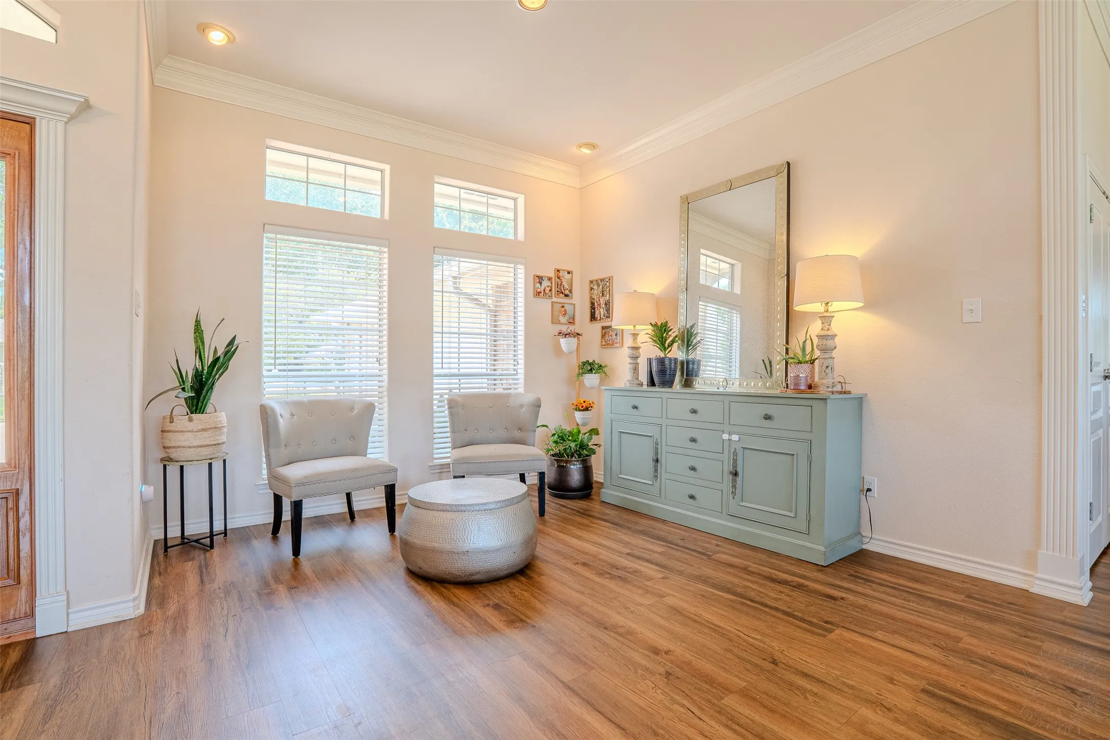 Wood-finish flooring, crown molding, recessed lighting, and multiple windows with blinds