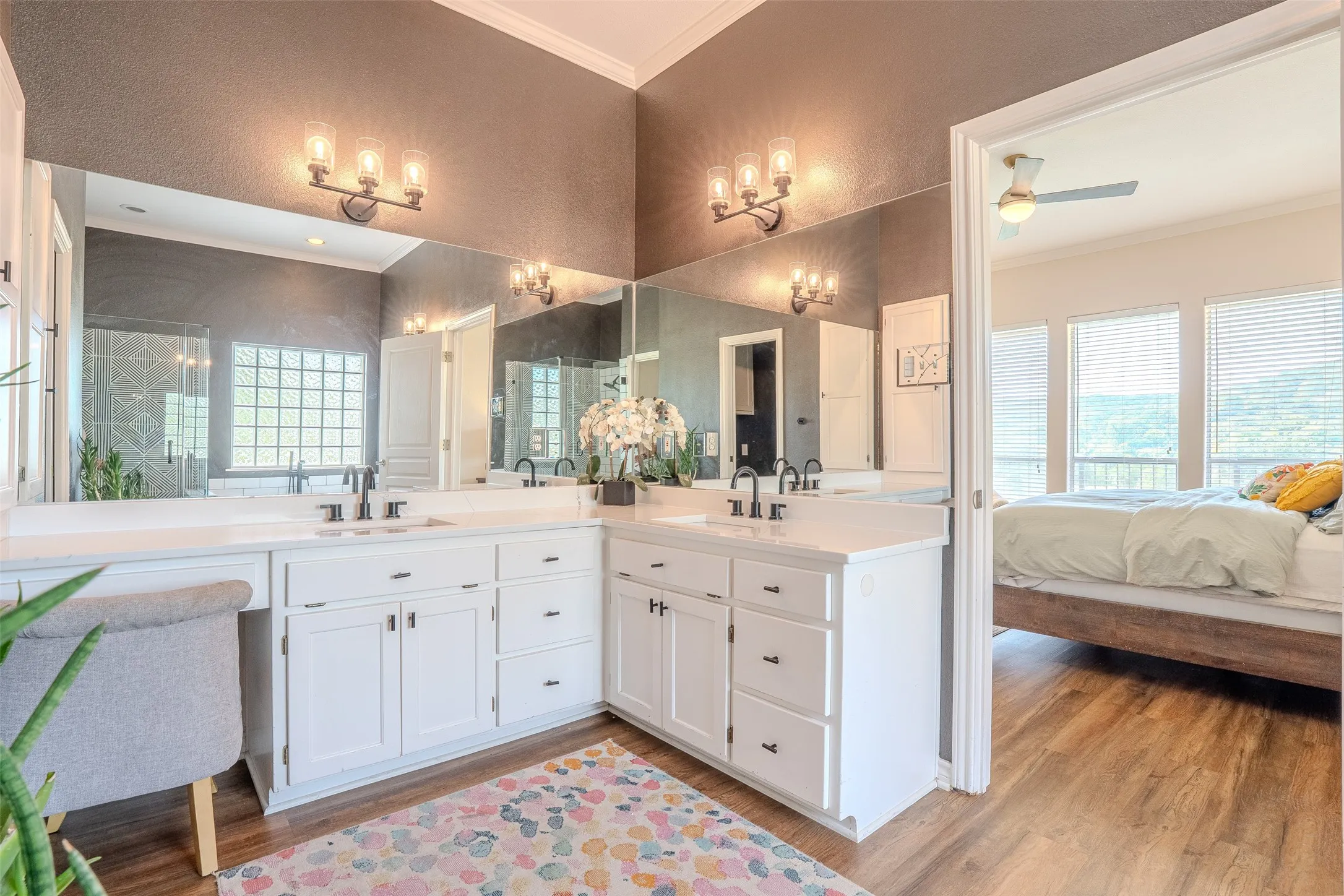 Dual vanity with integrated sinks, white cabinetry, and wall-mounted lighting