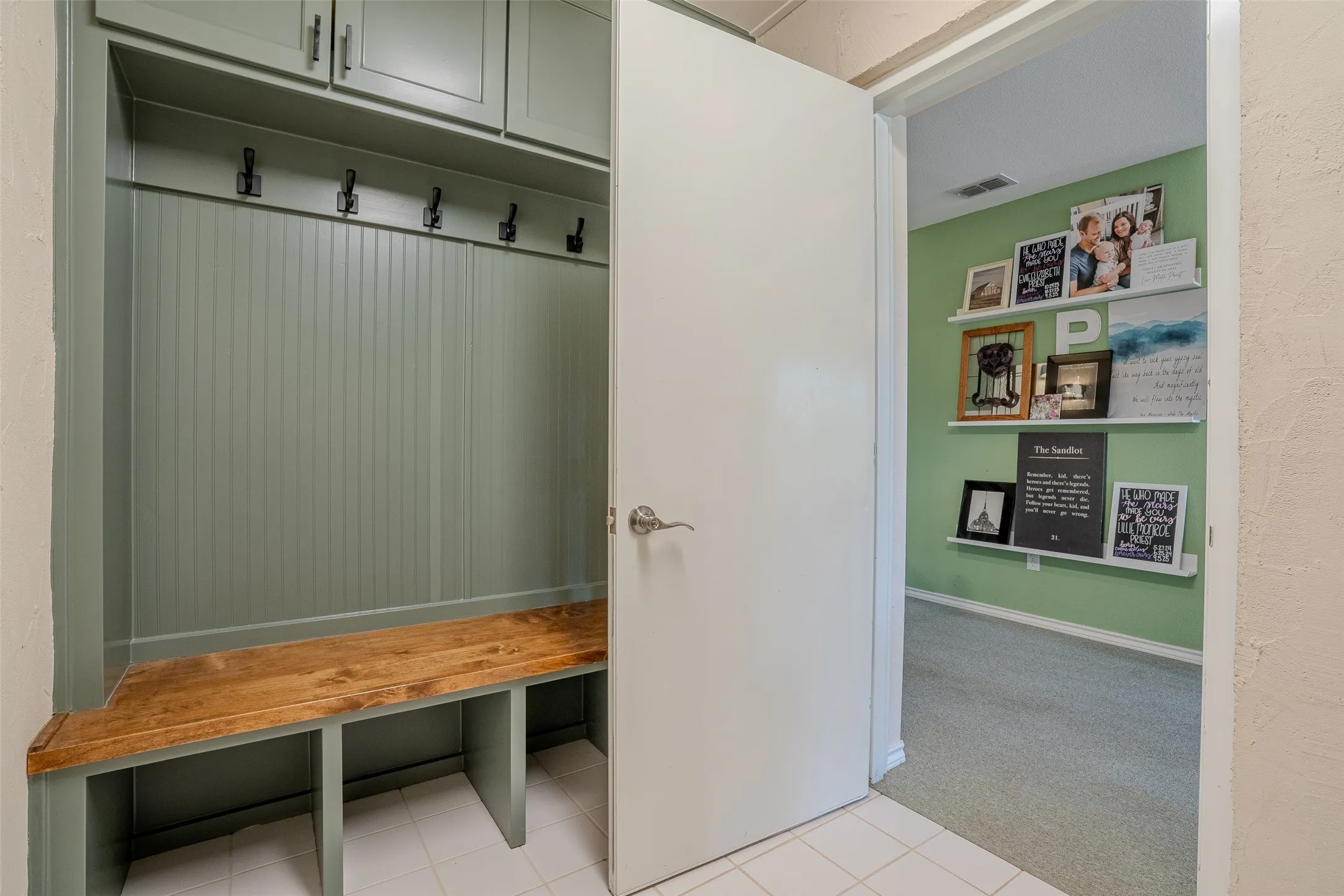 Built-in bench with integrated shelving, beadboard paneling, upper cabinetry, and wall-mounted hooks
