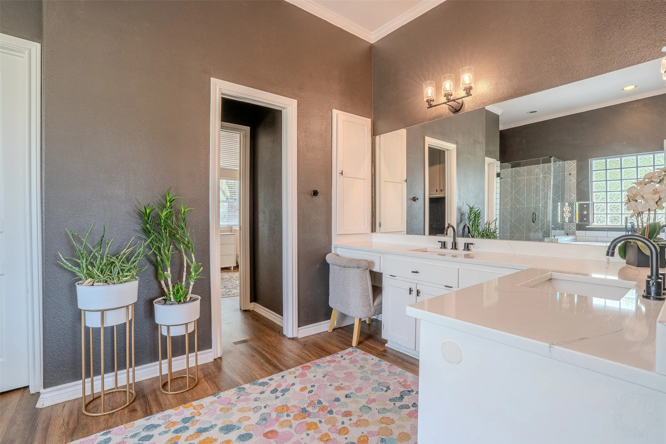 Expansive vanity with dual sinks, white countertops, built-in storage, and wood-finish flooring