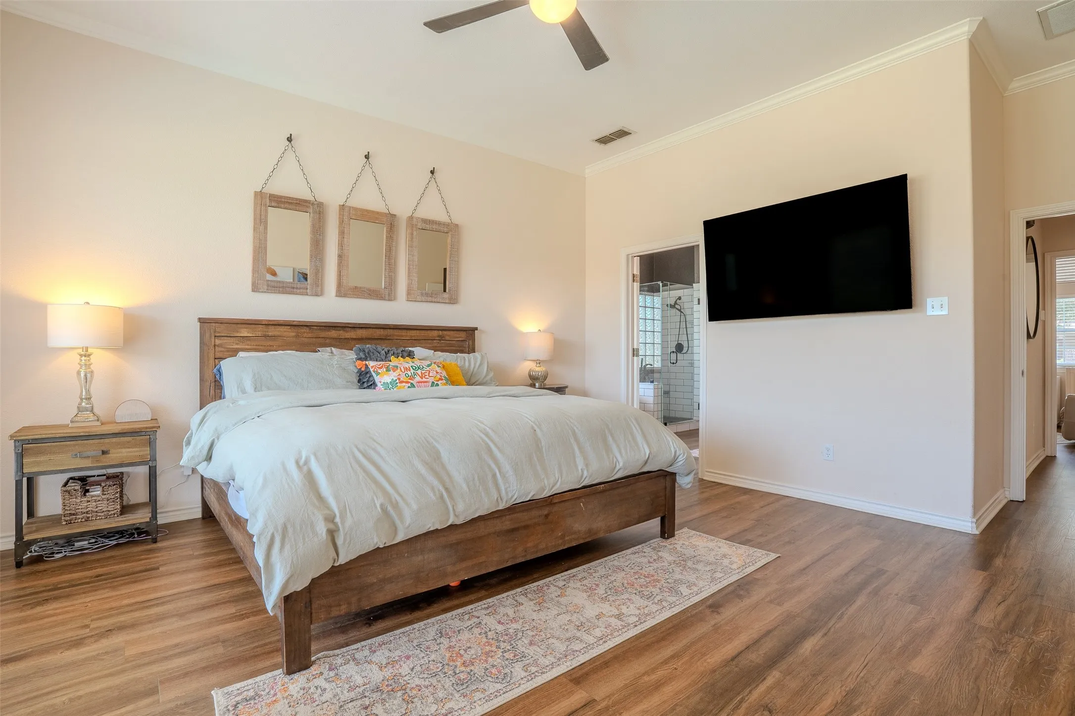 Wood-finish flooring, crown molding, ceiling fan, and a wall-mounted television