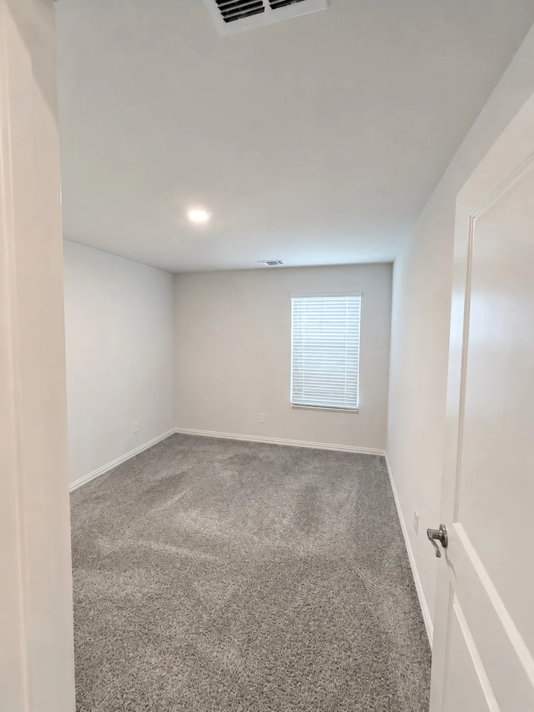 Recessed lighting, window with blinds, light gray wall paint, and gray carpeting