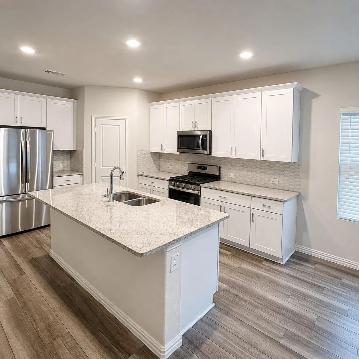 Contemporary kitchen featuring white cabinetry, stainless steel appliances, a center island with double sink, stone countertops, and wood-finish flooring