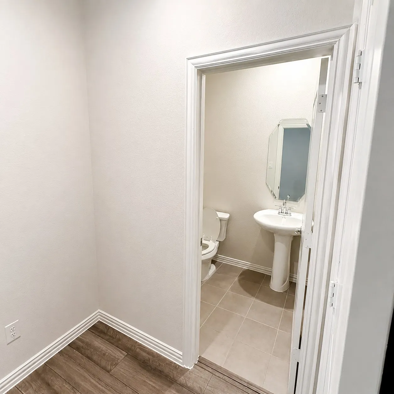 Pedestal sink, wall-mounted mirror, ceramic tile flooring, and a two-piece toilet