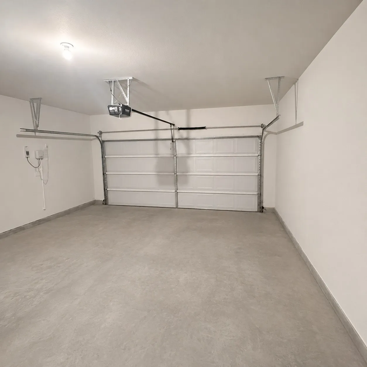 Attached garage featuring a white overhead door and light grey concrete flooring