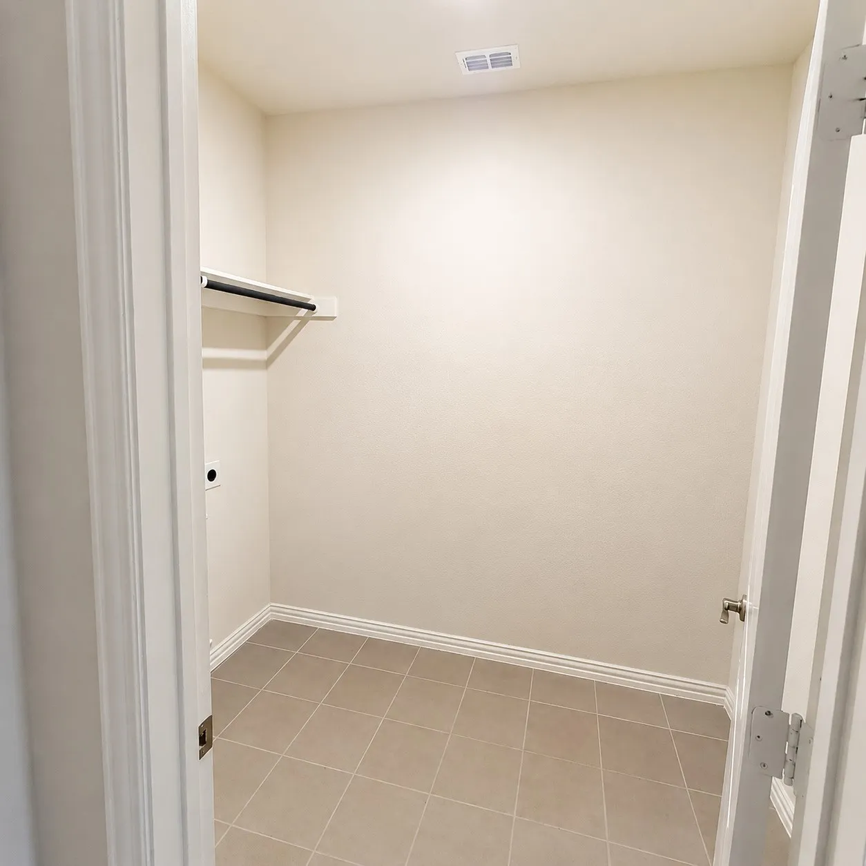 Utility room featuring tile flooring, neutral wall tones, a clothes hanging rod, and a ceiling light fixture