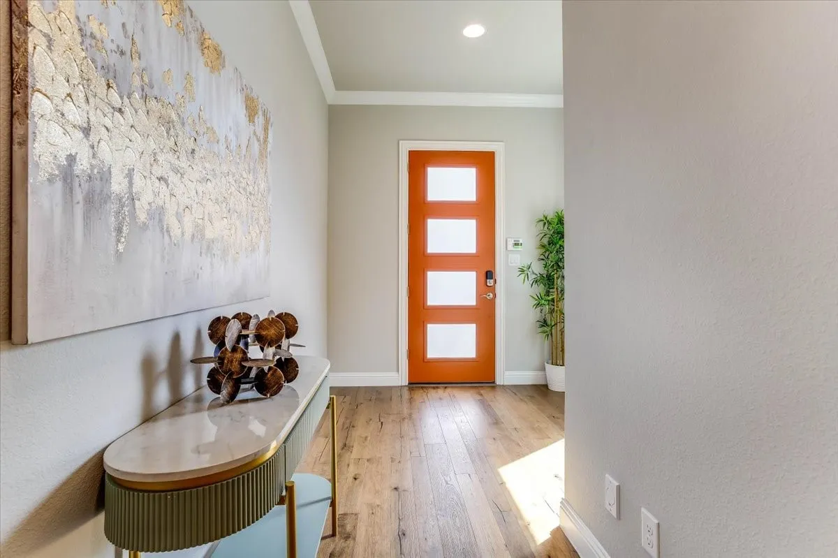 Inviting foyer greets guests with a statement making orange front door hardwood flooring, and spacious coat closet.