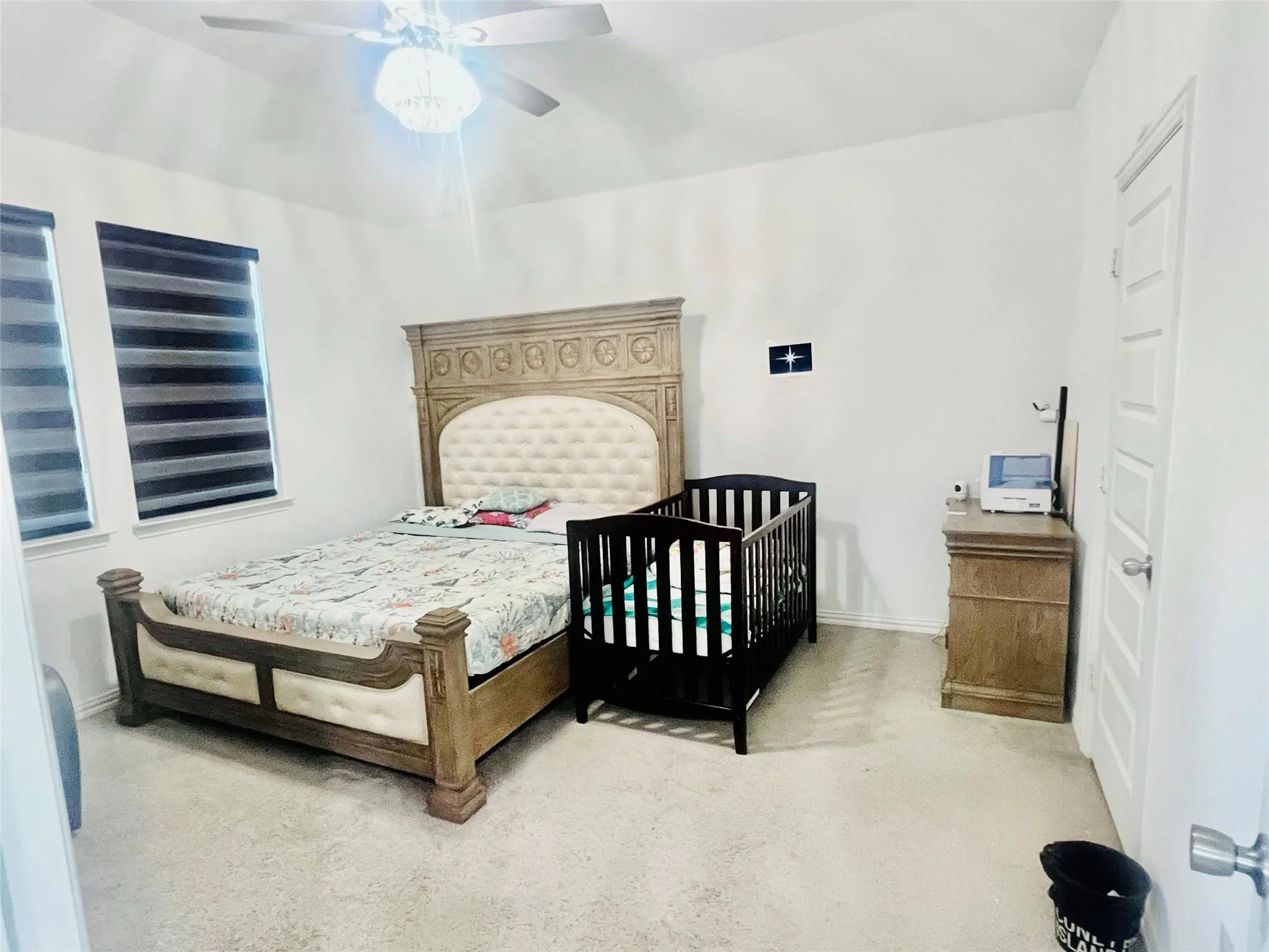 Carpeted room with white walls, two windows featuring horizontal blinds, and a ceiling fan with integrated lighting