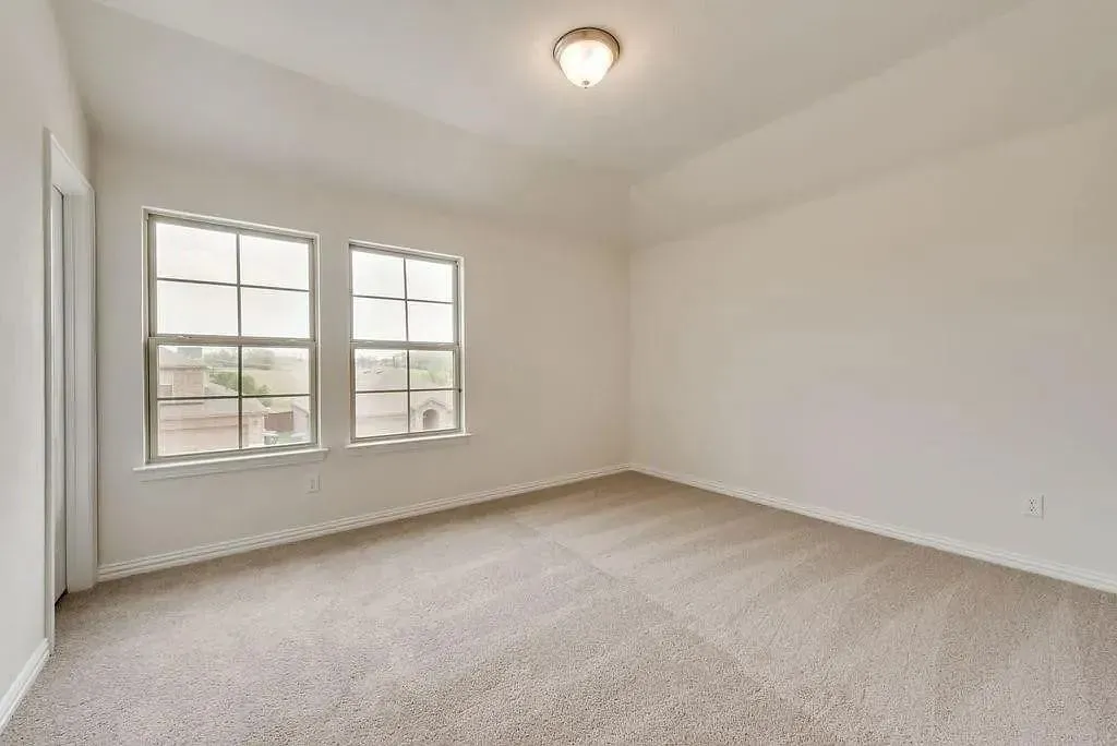 Recessed ceiling, neutral carpet flooring, two large windows, overhead flush-mount lighting, and light-toned wall finishes