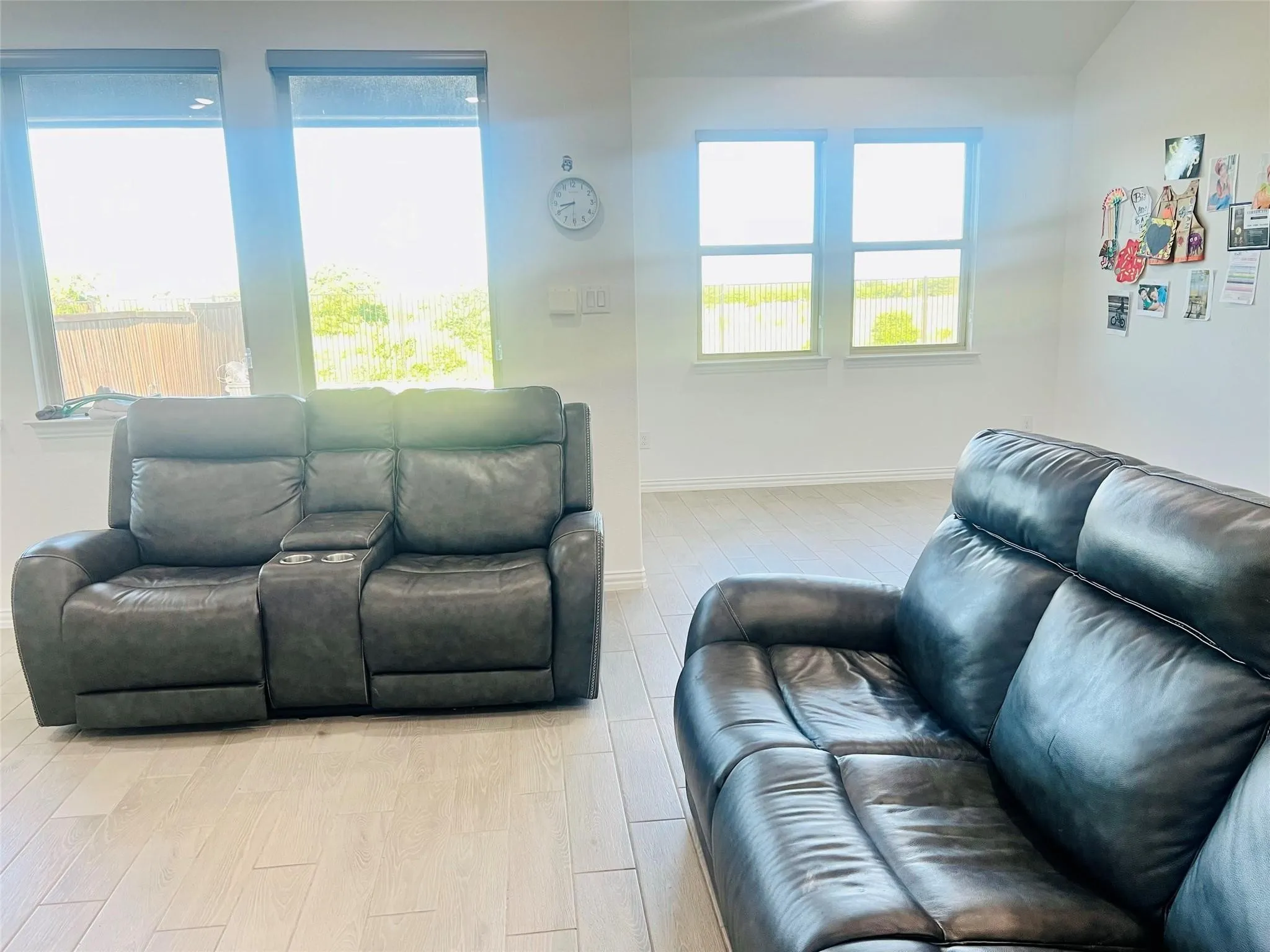 Light-toned flooring, white walls, and multiple windows with roller shades