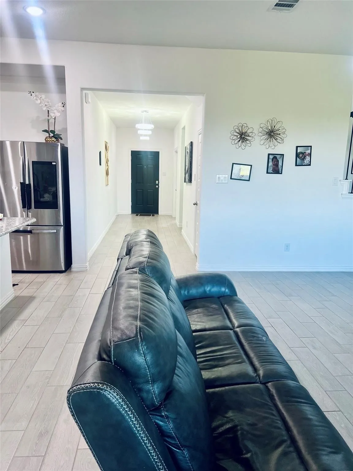 Wood-finish flooring throughout, recessed lighting, and a modern tiered flush mount light fixture