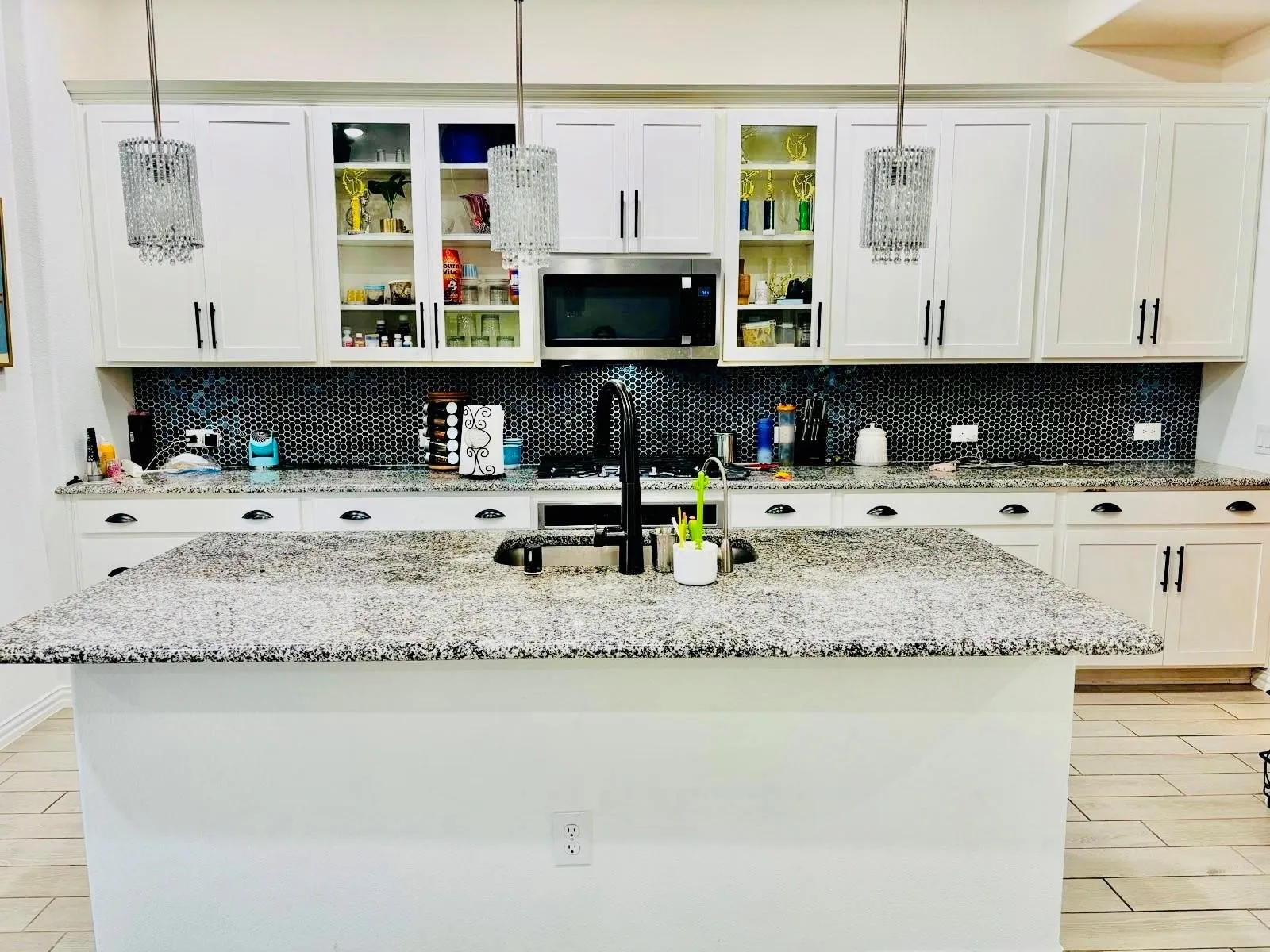White shaker cabinetry, dark hexagon tile backsplash, stainless steel appliances, pendant lighting, and granite countertops