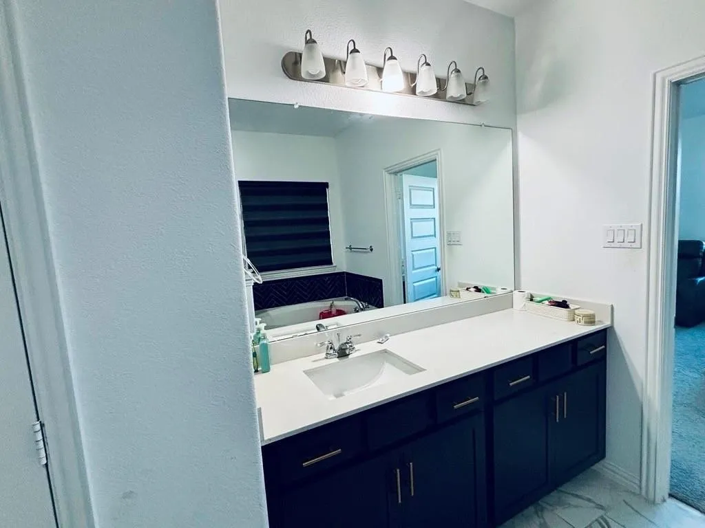 Double vanity with a white countertop and undermount sink, dark cabinetry, and gold-finish hardware