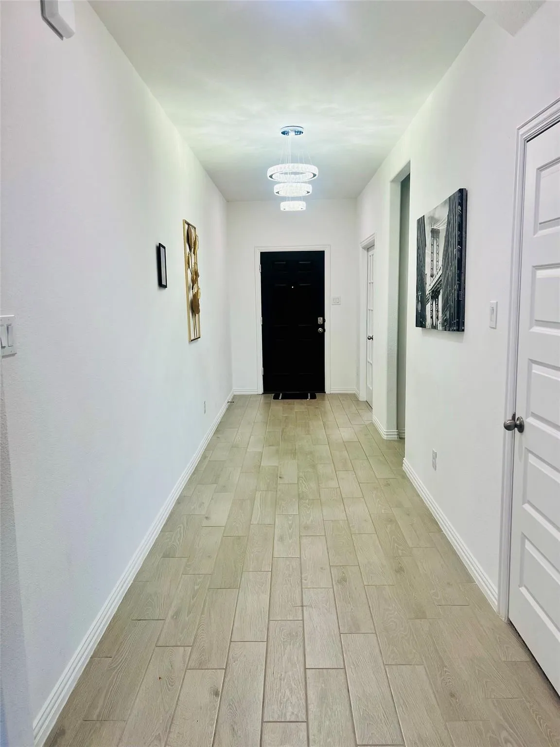 Hallway featuring plank-style tile flooring and multiple contemporary light fixtures