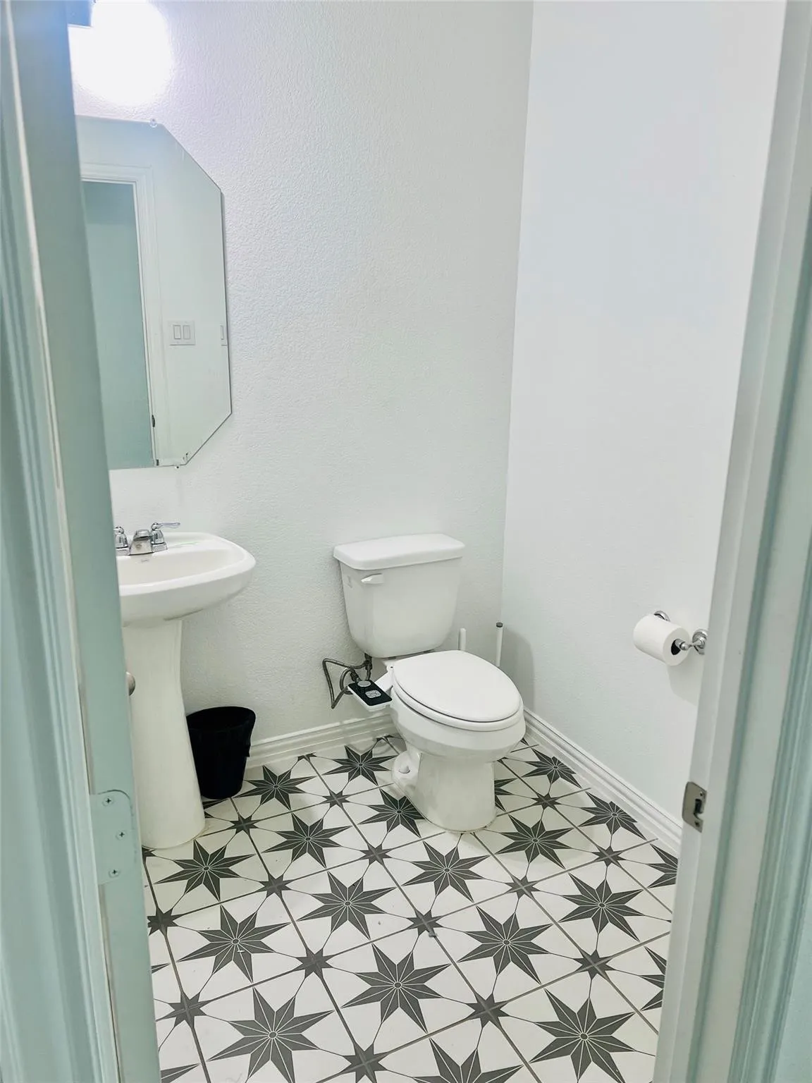 Pedestal sink with a chrome faucet, white commode, and decorative tile flooring