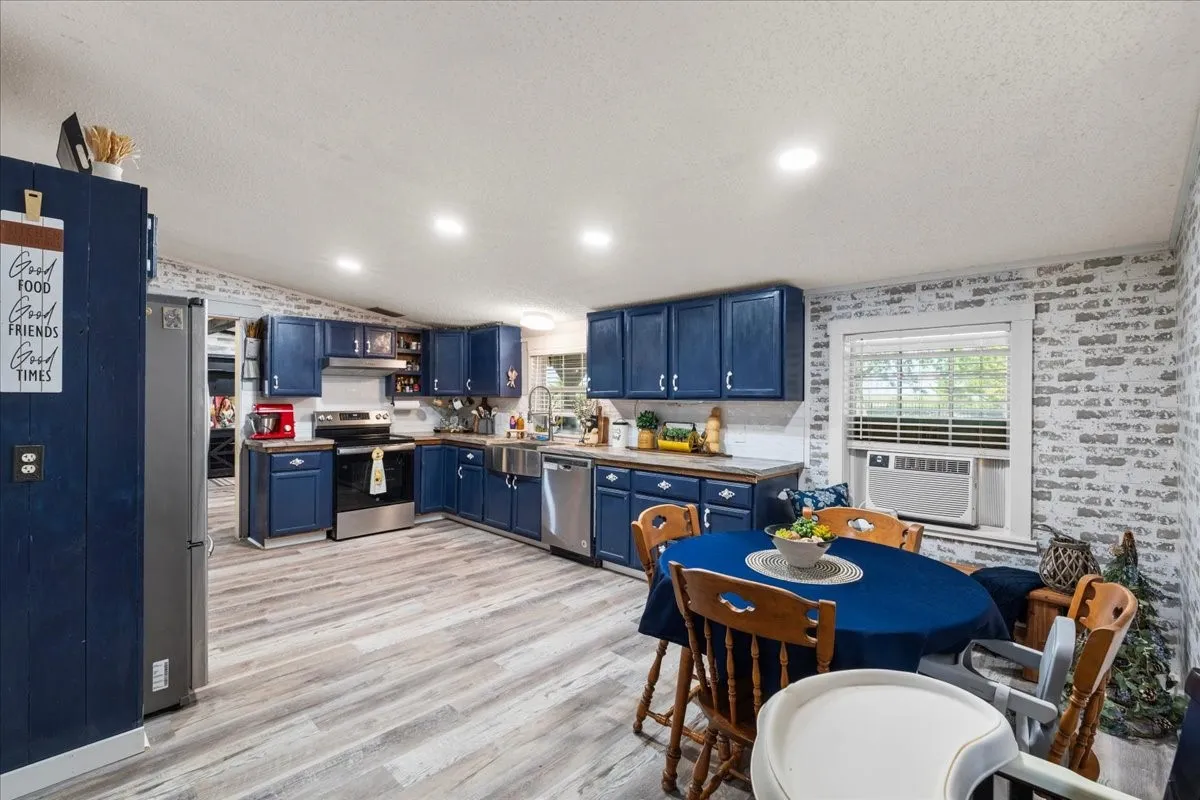 Kitchen featuring blue cabinetry, stainless steel appliances, wood-finish flooring, and a white subway tile backsplash