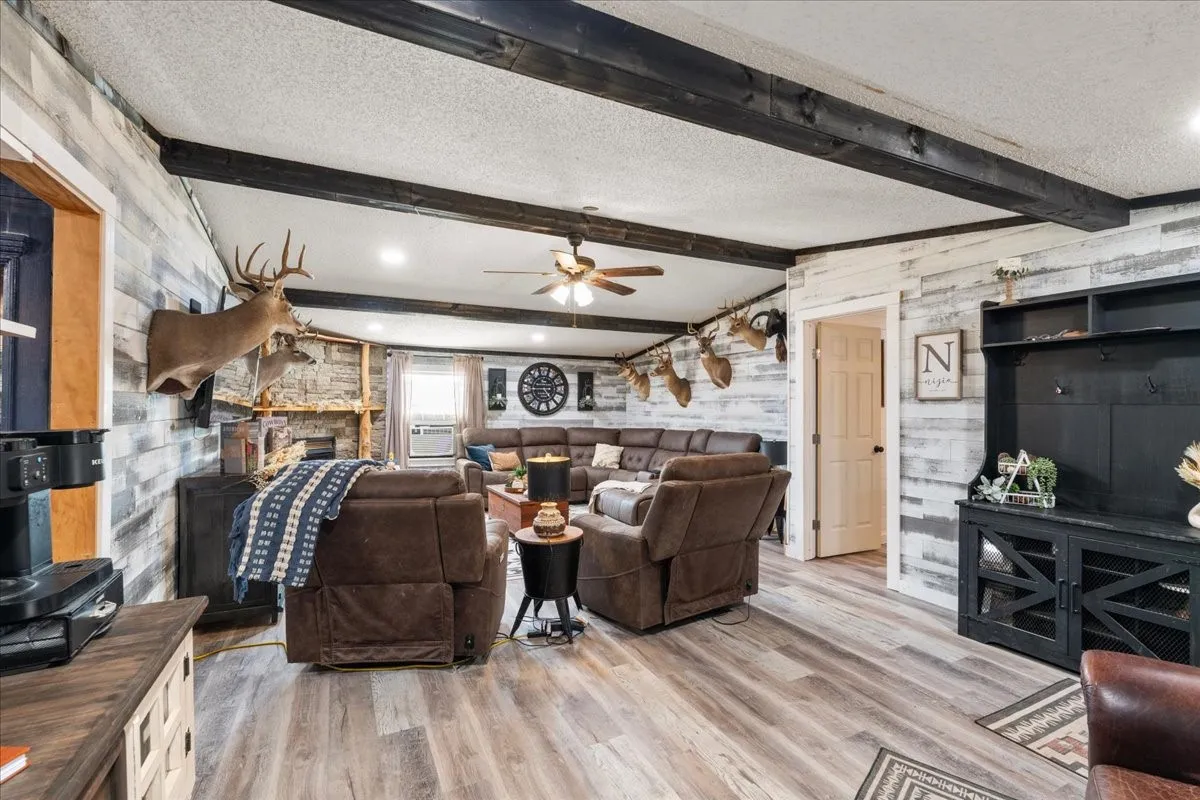 Recessed ceiling lighting, wood-finish flooring, exposed ceiling beams, and a ceiling fan