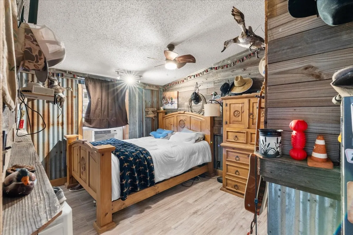 Spacious living area featuring wood-finish flooring, shiplap-style wall paneling, and exposed ceiling beams