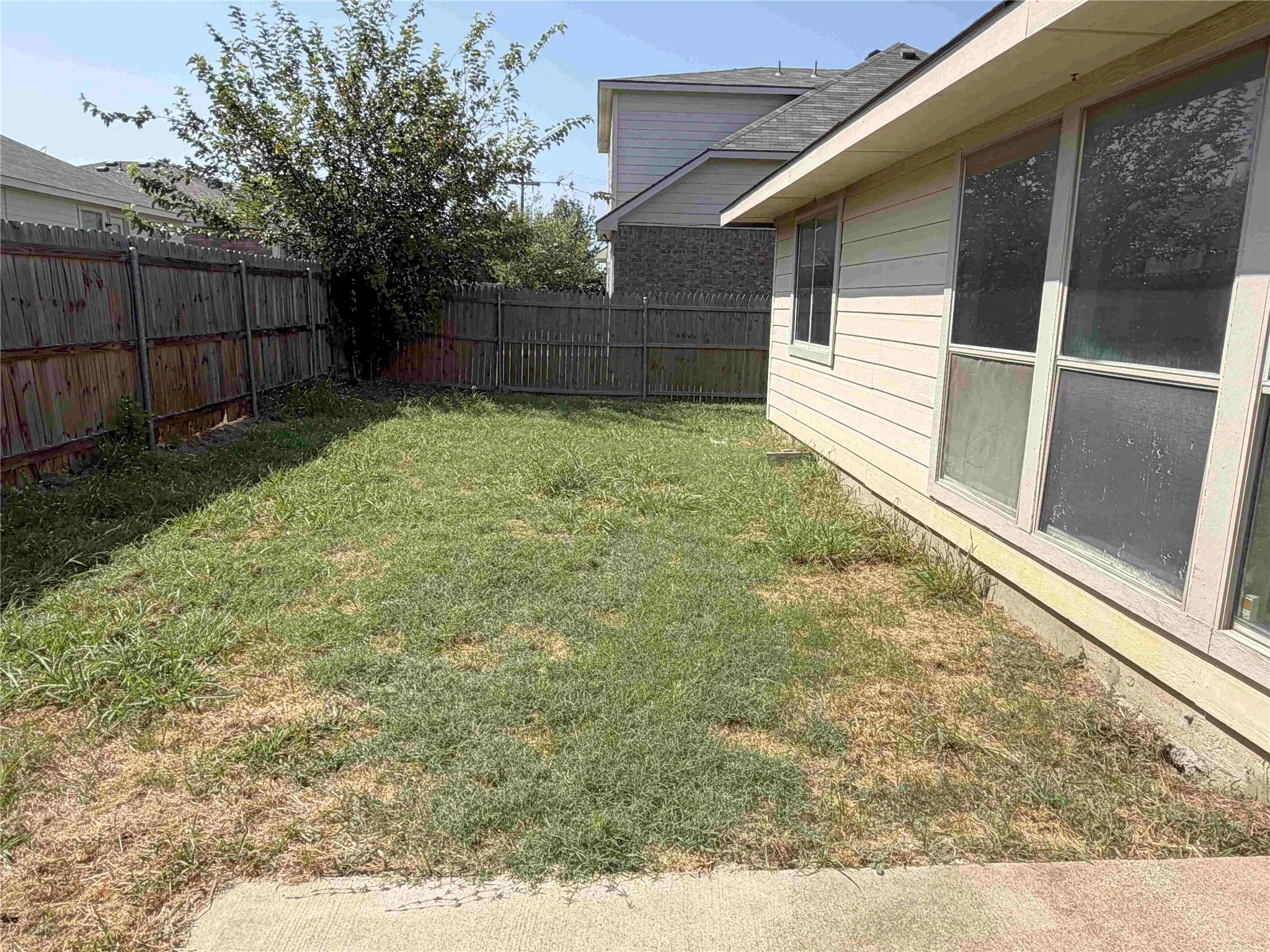 Wood privacy fencing, concrete patio, exterior siding, and multiple windows