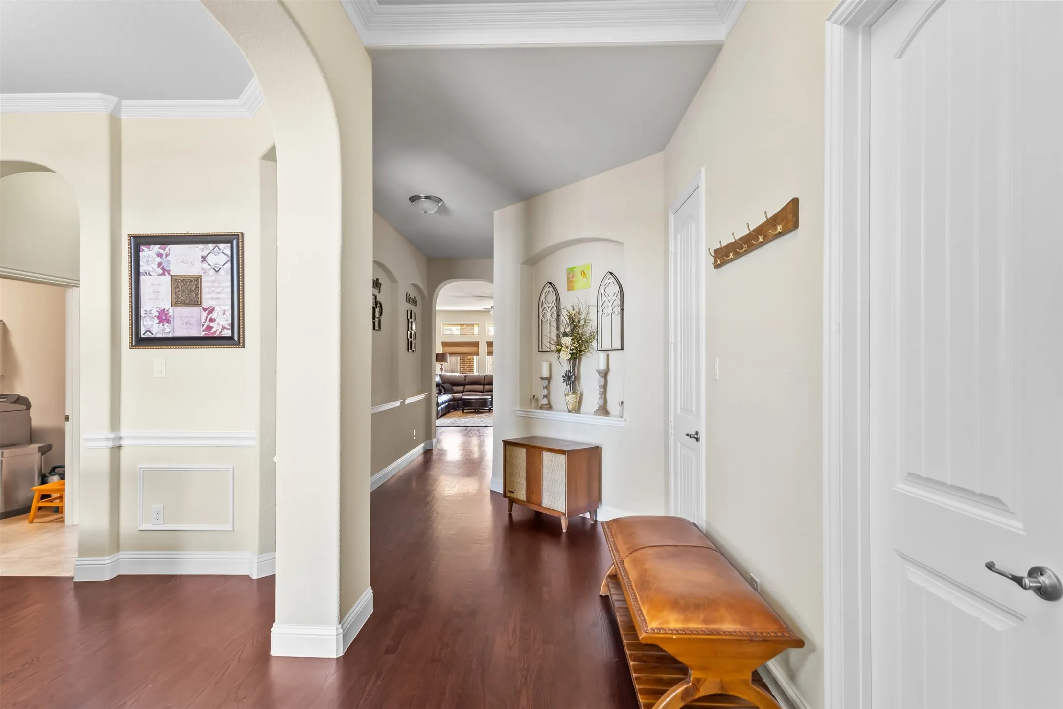 Wood-finish flooring, arched doorways, crown molding, chair rail molding, and recessed wall niche