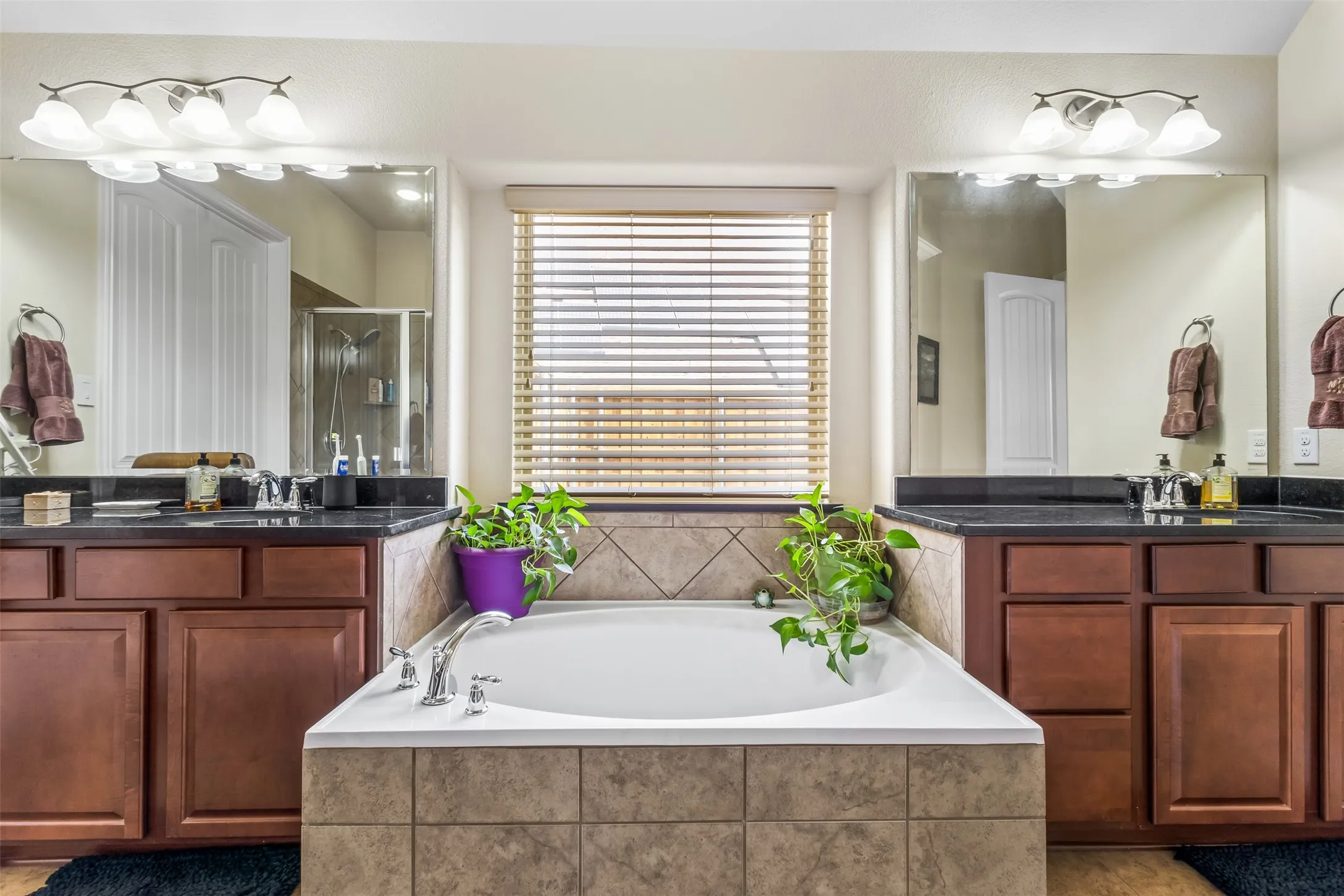 Dual vanity with dark wood cabinetry and black countertops