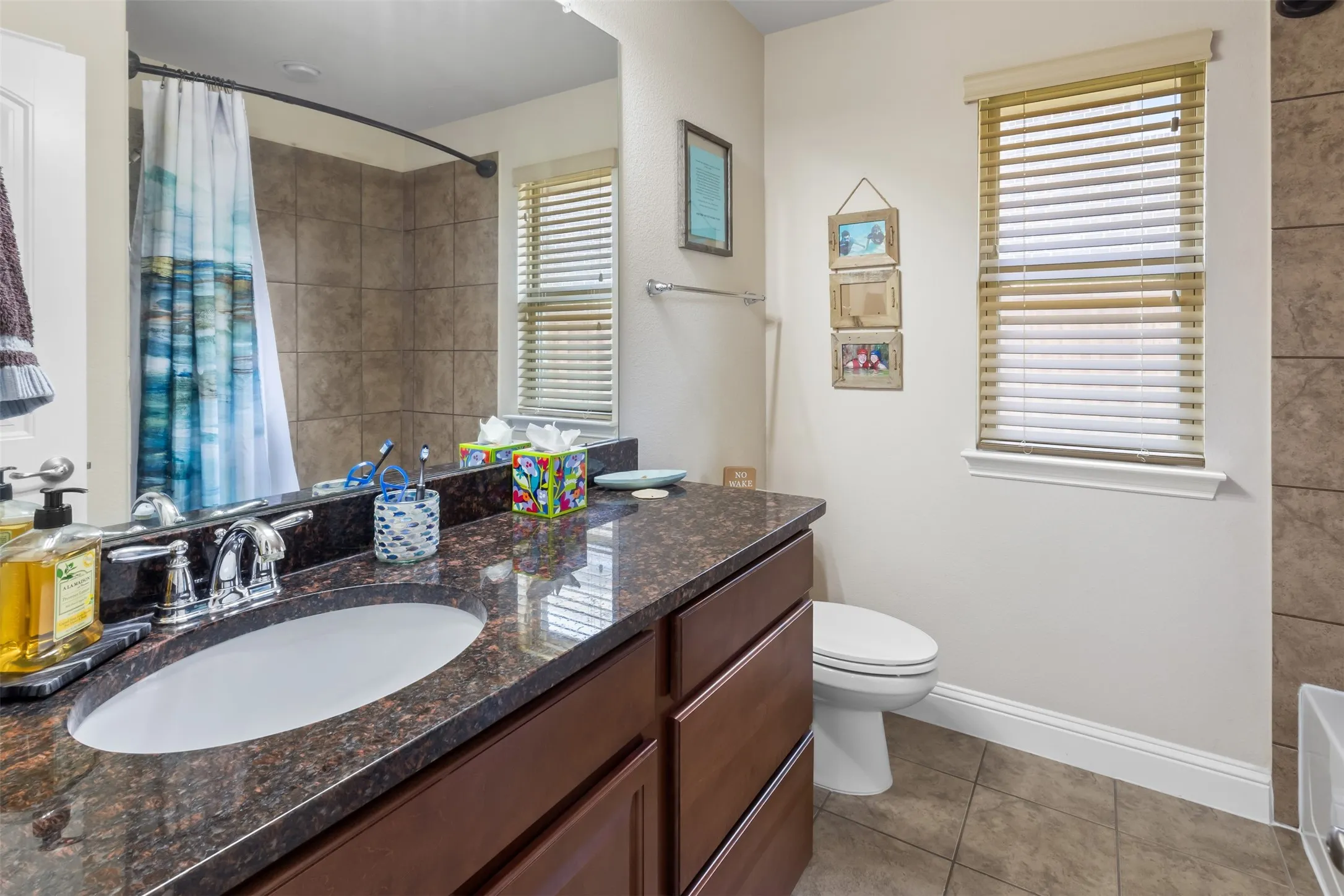 Dark wood-finish vanity with an undermount sink, a polished chrome faucet, and a polished stone countertop