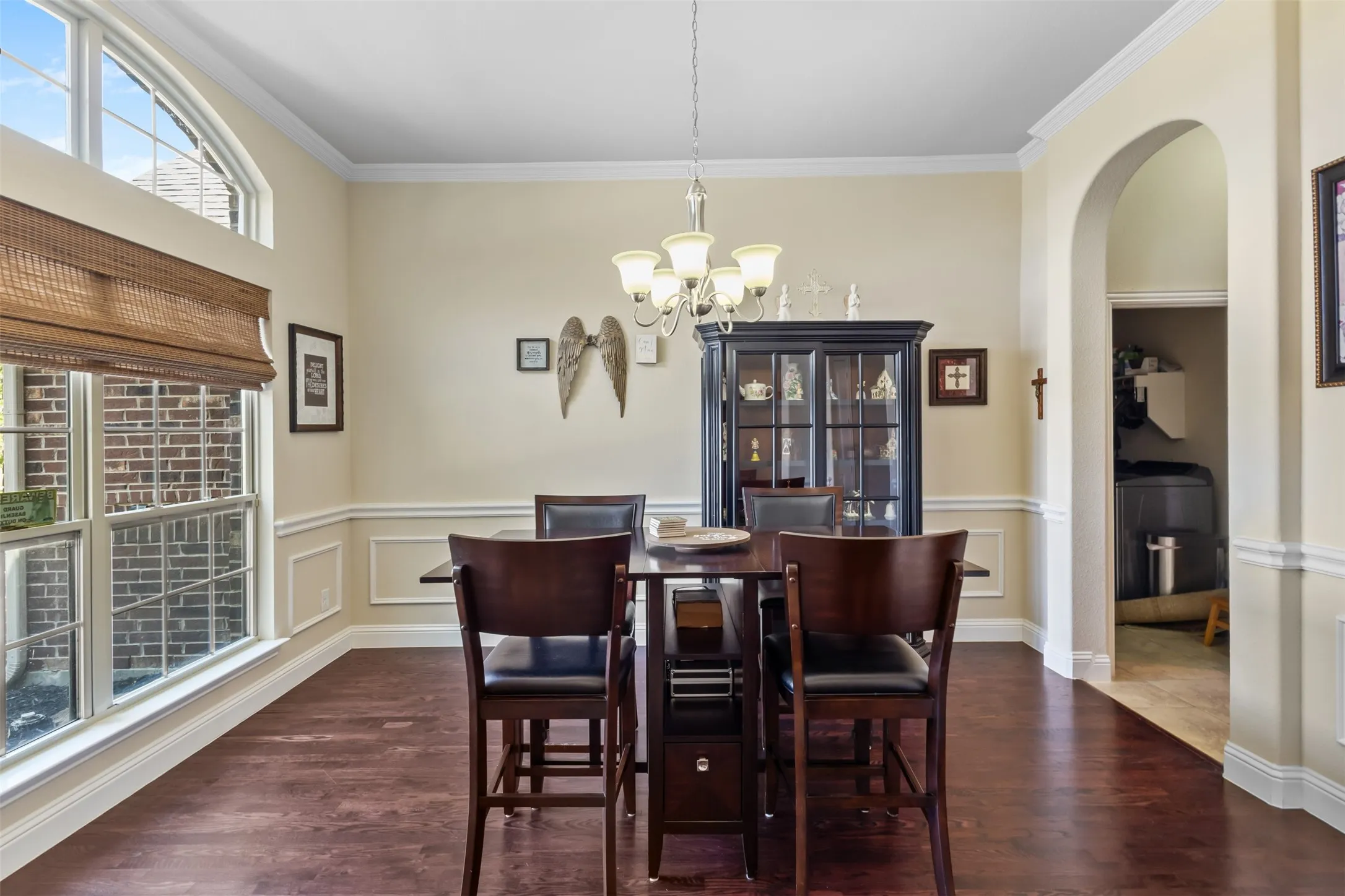 Wood-finish flooring, wainscoting, crown molding, and an arched doorway
