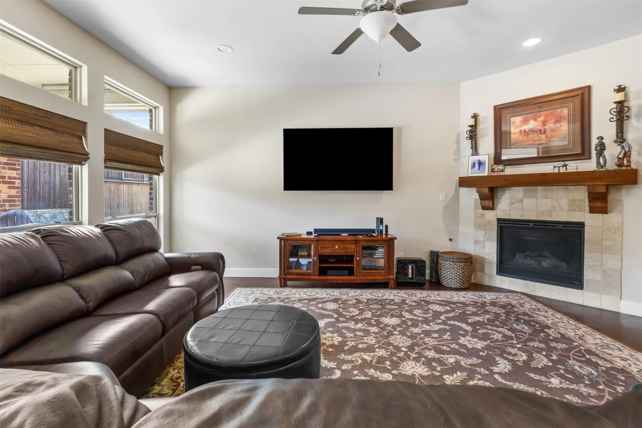 Hardwood flooring, tiled fireplace with wood mantel, high ceilings, recessed lighting, and ceiling fan